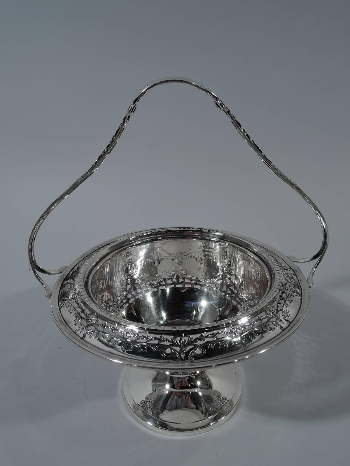 American Edwardian sterling silver basket bowl. Curved bowl with turned down rim, raised foot, and stationary handle with split mounts. Pierced and engraved floral and foliate ornament as well as geometric piercing. Handle has tubular frame