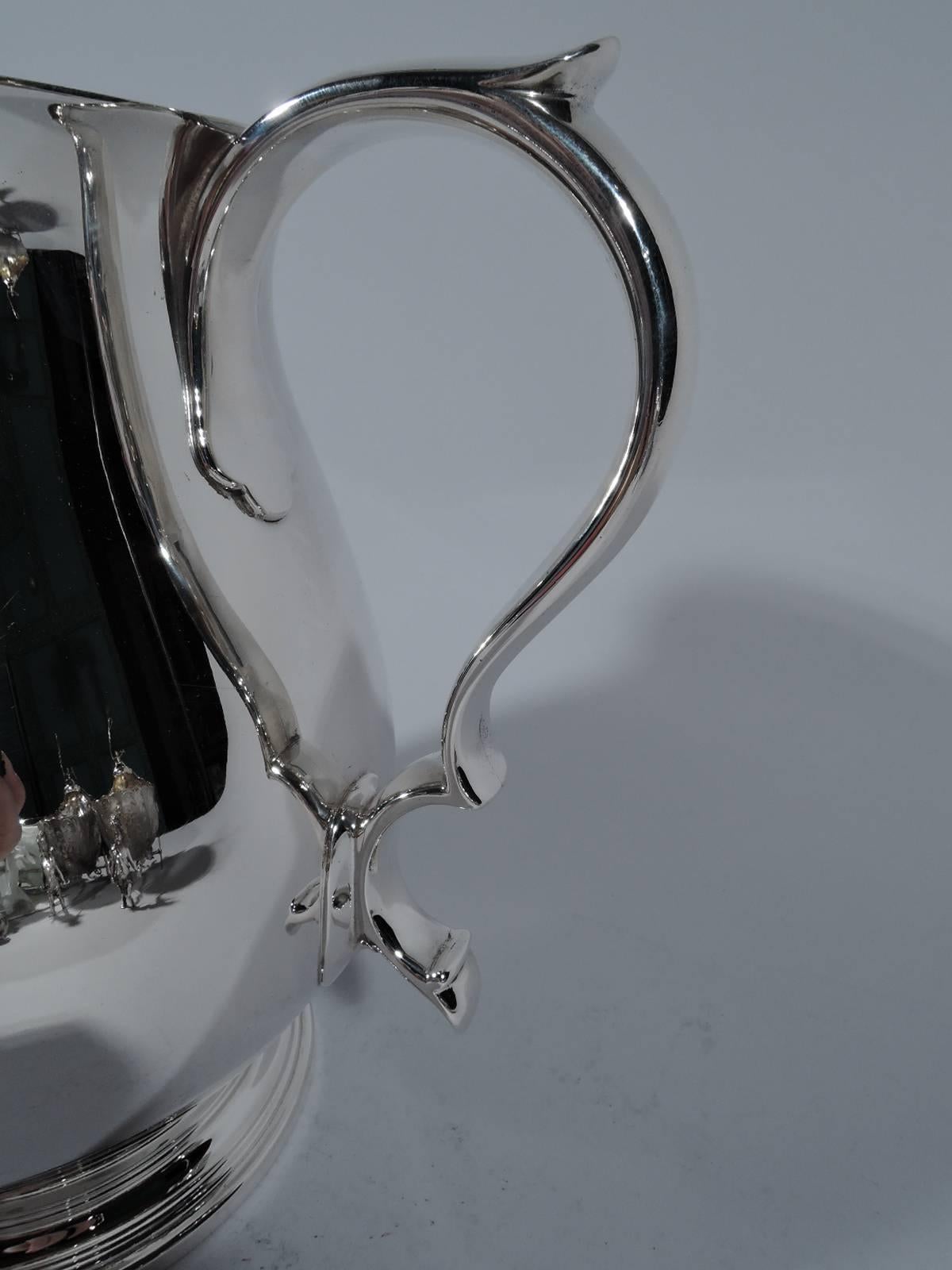 Stylish Modern sterling silver water pitcher. Made by Tiffany & Co. in New York. Curved body, flared, rim, capped double-scroll handle, and stepped foot. Spare and supple with a distinctive V-Form spout on front. Hallmark includes pattern no. 19873