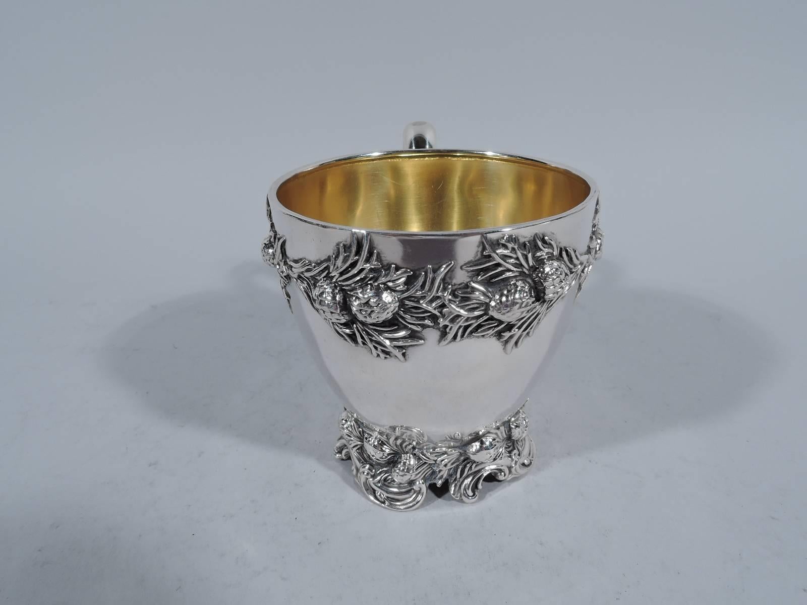 Sterling silver baby cup. Made by Black, Starr & Frost in New York, circa 1890. Tapering bowl, scroll handle, and raised foot. Pine branch with cones applied to rim and foot. Gilt interior. Hallmark includes no. 2871. Weight: 5.4 troy ounces.
