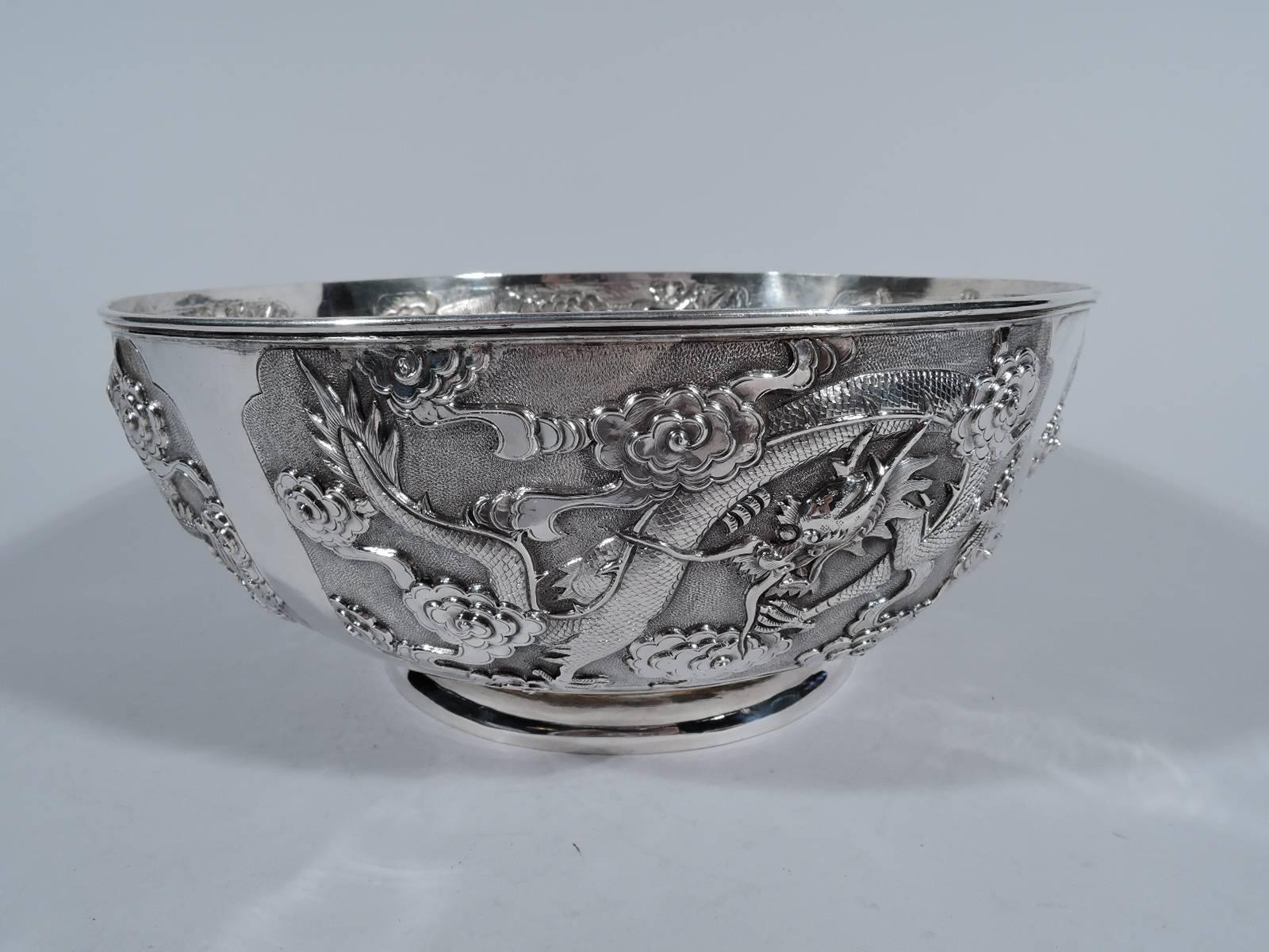 Fine quality Chinese export silver bowl, circa 1900. Curved sides and raised and spread foot. Four shaped frames inhabited by scaly, slithering dragons and clouds on stippled ground. Marked with Chinese characters and 3 letters of which the last two