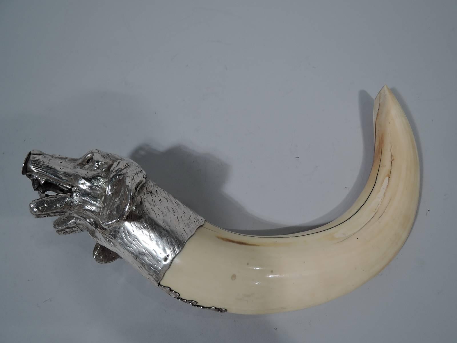 Rare and wonderful tusk cigar cutter with silver mount, circa 1890. Mount in form of two cheek-by-cheek dogs’ heads with floppy ears and eager red-glass eyes. Blades concealed in mouths, which also have some major dentition. Cigar inserted in snout
