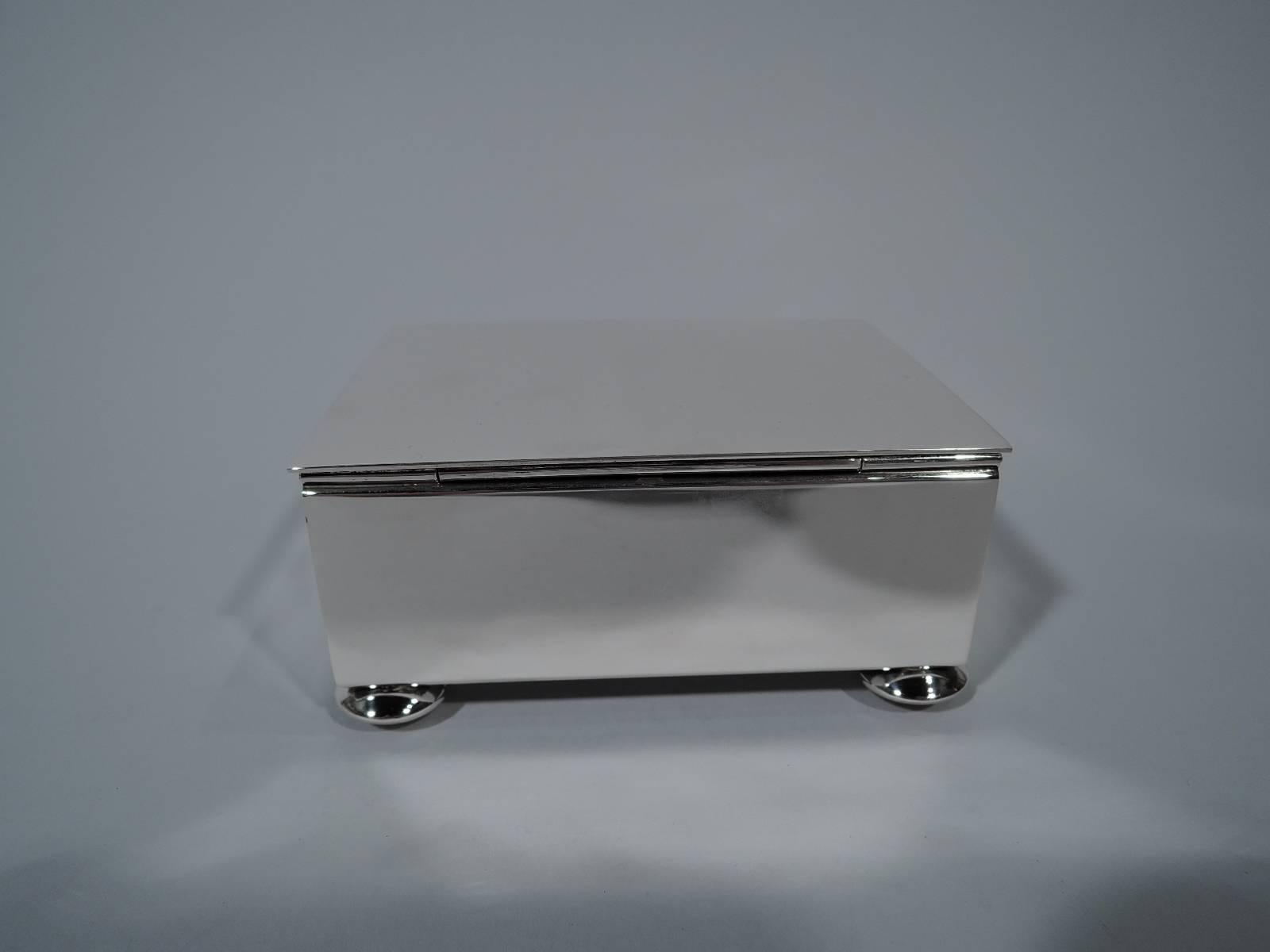 Mid-Century Modern sterling silver box. Made by Tiffany & Co. in New York. Rectangular with straight sides. Cover flat and hinged with slightly overhang. Rests on four squashed ball supports. Box interior cedar-lined. Hallmark includes postwar