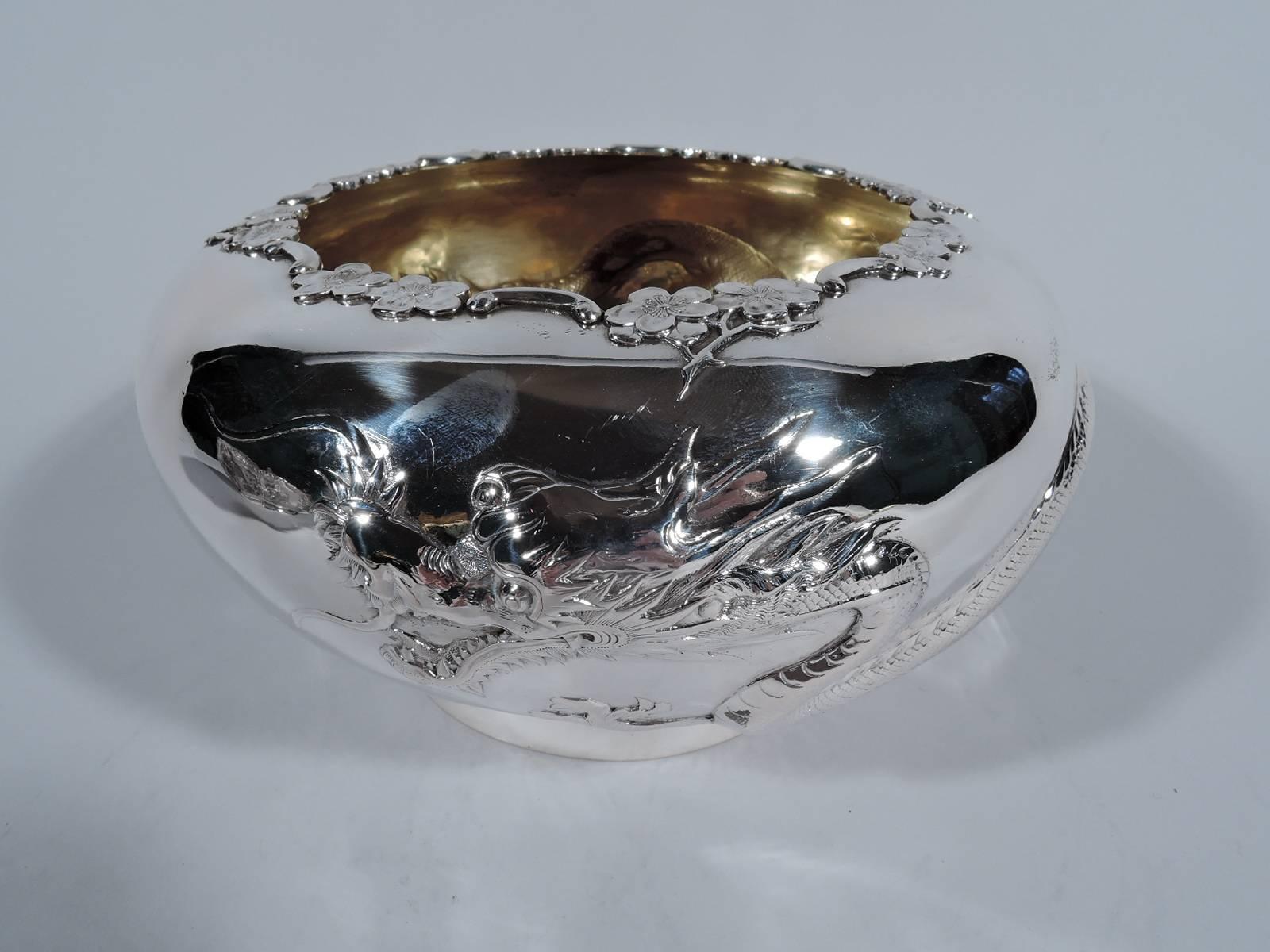 Chinese export silver bowl, circa 1900. Curved sides with turned-in mouth and spread foot. Exterior encircled with slithering, scaly, and horned dragon. Mouth rim has blossoming prunus branch. Interior lightly gilt. Hallmarked with Chinese