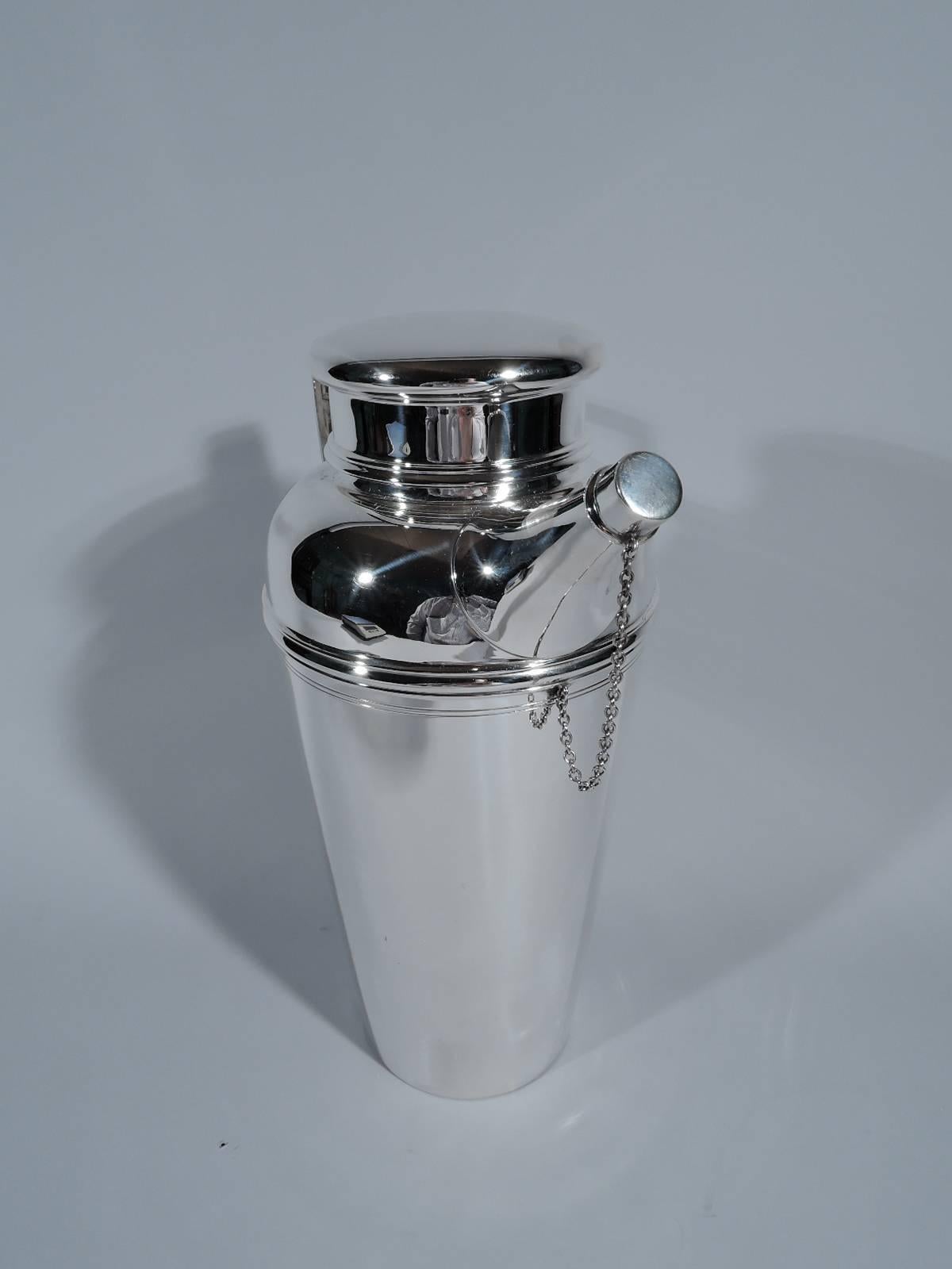 Party-size sterling silver cocktail Shaker. Made by Tiffany & Co. in New York, circa 1929. Tapering bowl, scrolled-bracket handle, diagonal spout with built-in strainer and chained cap, and short neck with bun cover. Holds four pints. Hallmark