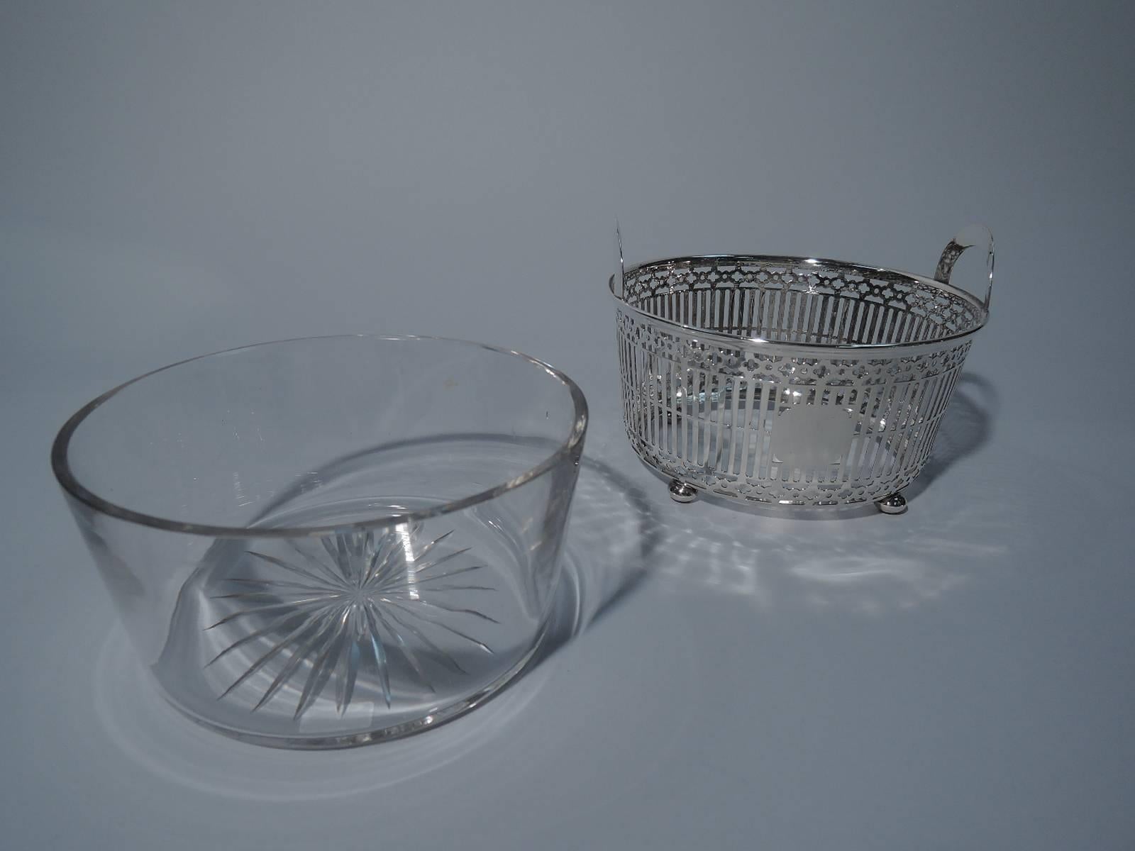Sterling silver ice bucket. Made by Meriden Britannia (part of International) in Meriden, Conn., circa 1920. Basket-form with geometric piercing and arched handles mounted to rim. Rests on 4 ball feet. Clear glass liner. Hallmark includes no. 354.