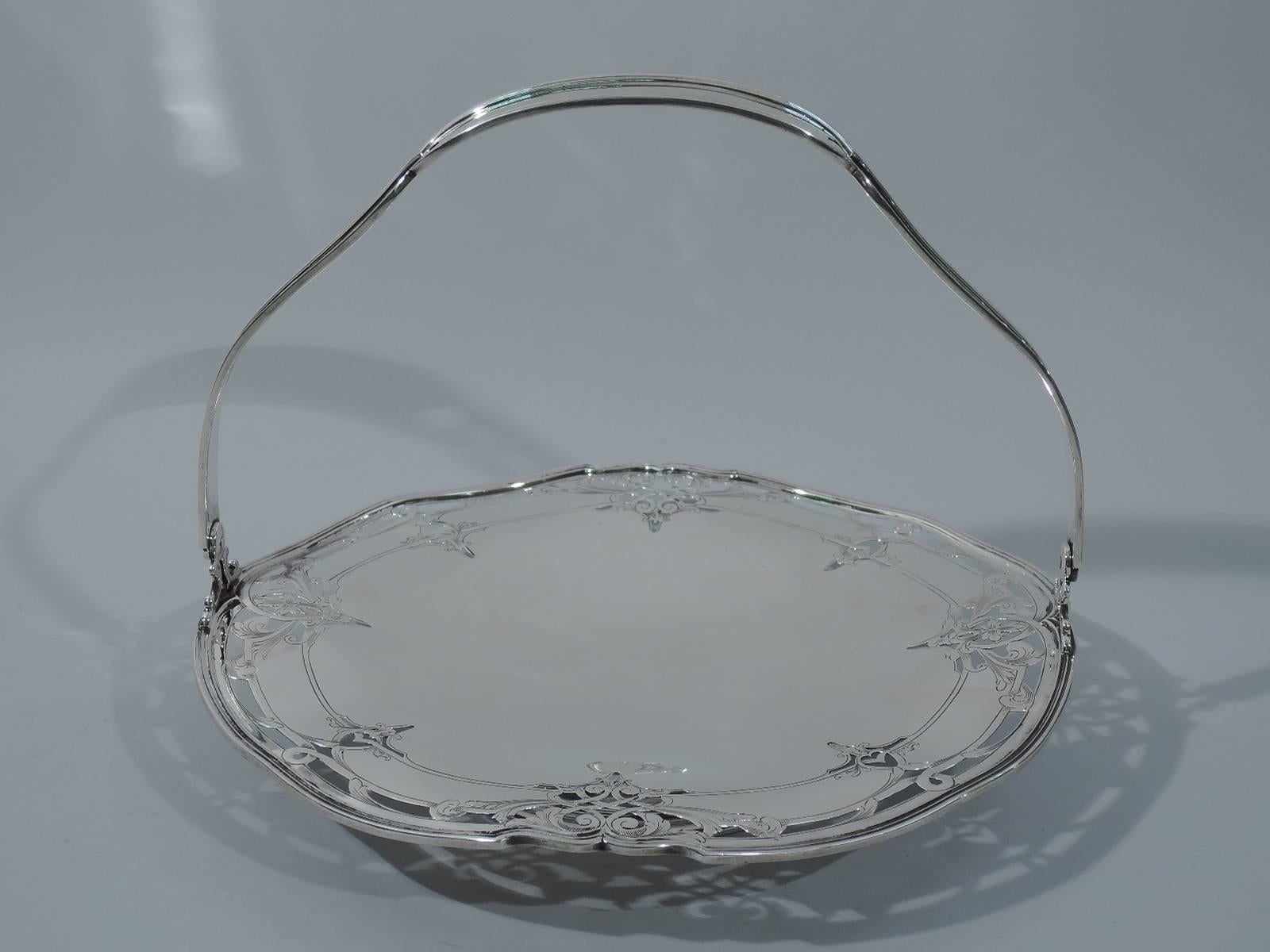 Lovely sterling silver cake plate with swing handle. Made by Reed & Barton in Taunton, circa 1920. Undulating and reeded rim with scrolls and pierced ornament. Plain well for showing off special treats. C-scroll handle is reeded with concave sides,