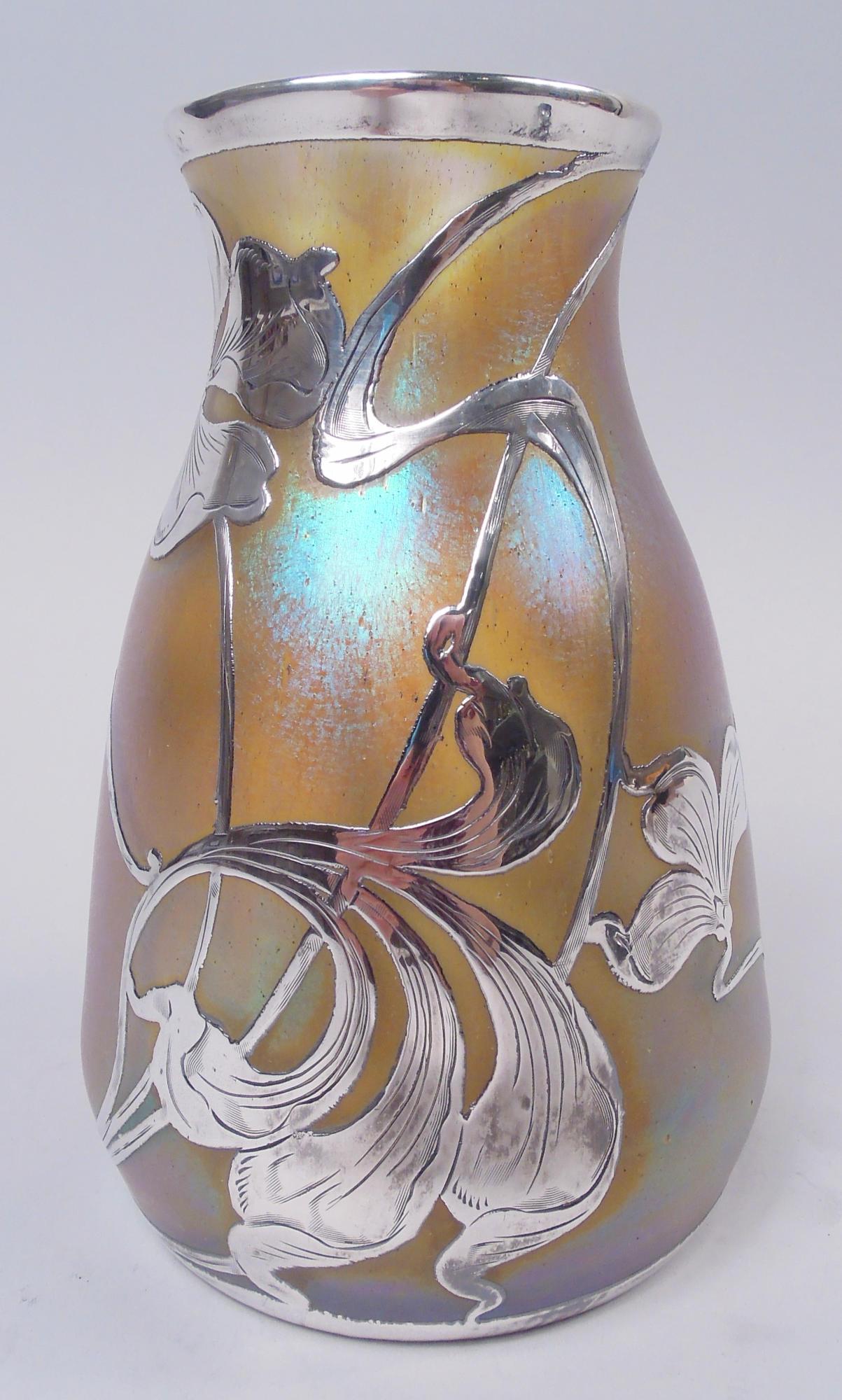 Art Nouveau glass vase with engraved silver overlay. Made by Quezal in New York, ca 1900. Ovoid with gently flared mouth rim. Open overlay with loose and distended blooms and entwined and whiplash tendrils. Glass iridescent gold shading to blue.