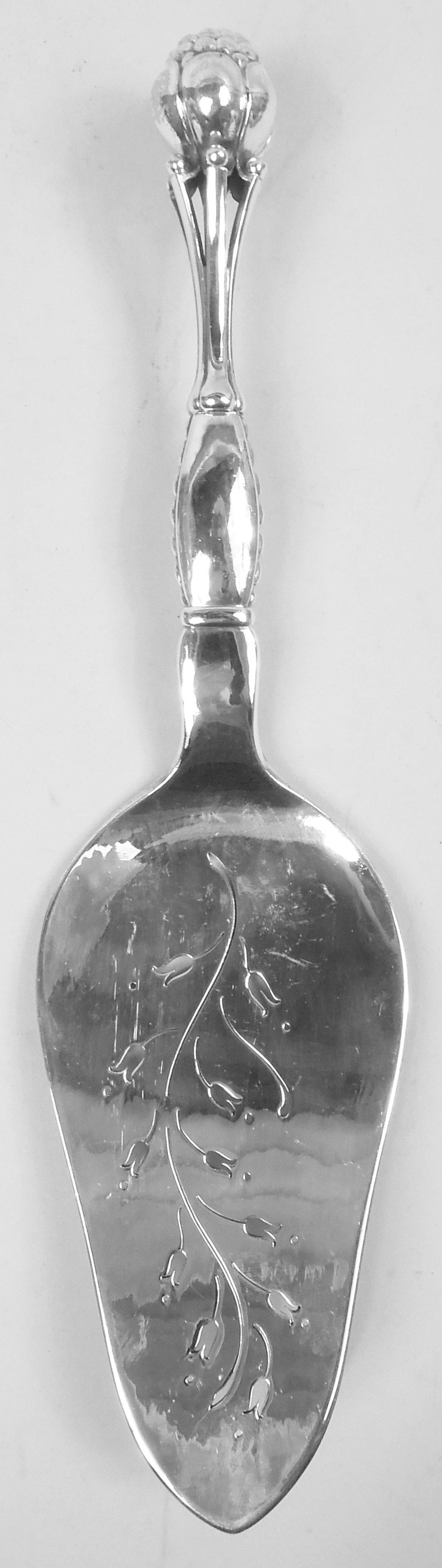 Danish Modern sterling silver fish serving pair comprising fork and slice. Made by Georg Jensen in Copenhagen. Each: Berry terminal on open tendrils mounted to wide and curved beaded stem; pierced and engraved flowering branch on shank and blade.