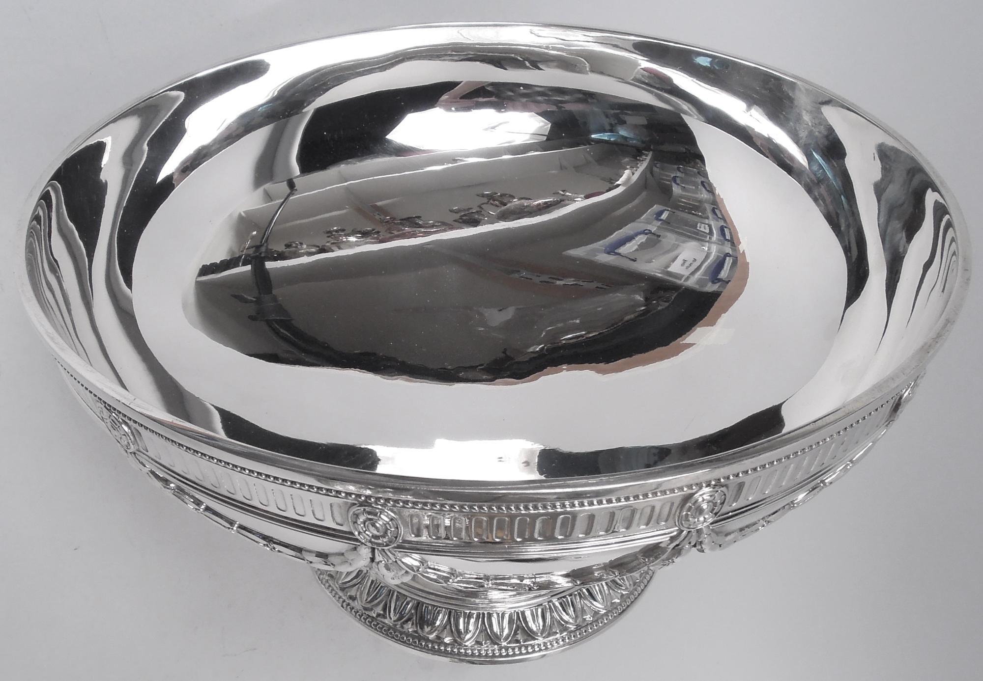 Edwardian Regency sterling silver centerpiece bowl. Made by Tiffany & Co. in New York, ca 1935. Wide and curved on raised foot. On bowl, paterae with pendant swags mounted to colonnade band; on foot, leaf-and-dart band. Beaded and reeded borders.