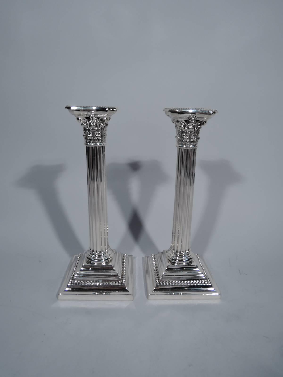 Pair of neoclassical sterling silver candlesticks. Made by Gorham in Providence in 1909. Each: fluted column surmounted by composite capital. Detachable bobeche concave and chamfered with beaded rim. Stepped and square base also beaded. A great old