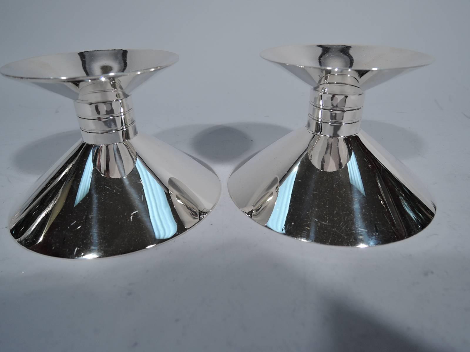 Pair of modern sterling silver candlesticks. Made by Tiffany & Co. in New York. Small and shallow cone inverted on short cylinder with incised banding in turn mounted to large and shallow cone. Harmonious geometry. Hallmark includes pattern no.