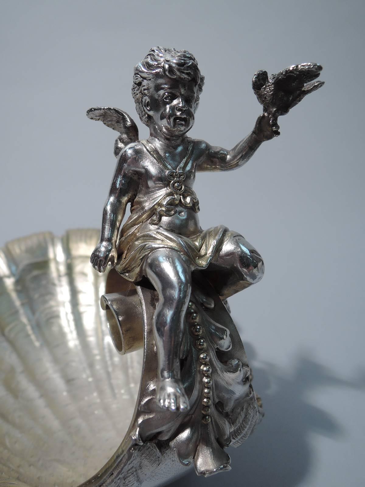 German 800 silver bowl, circa 1900. Shell form with flutes and tiered striations, terminating in volute scroll. Mounted to scroll is cast figure of winged and chubby cherub with bird perched on raised hand. Bowl interior has light gilt wash as does