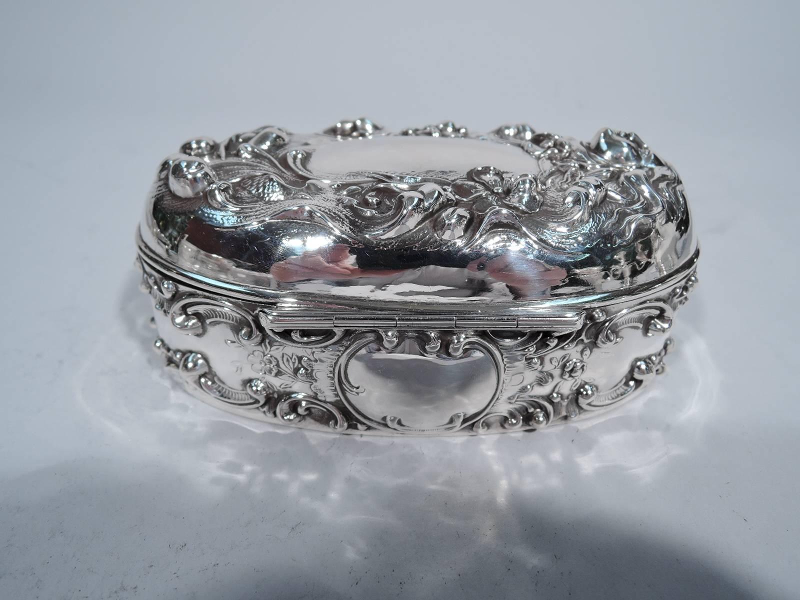 Art Nouveau sterling silver boudoir box. Made by Mauser in New York, circa 1890. Oval with hinged cover. Chased and repoussé ornament. On sides scrolls and flowers. On cover a face that appears to float Ophelia-like surrounded by flowers and