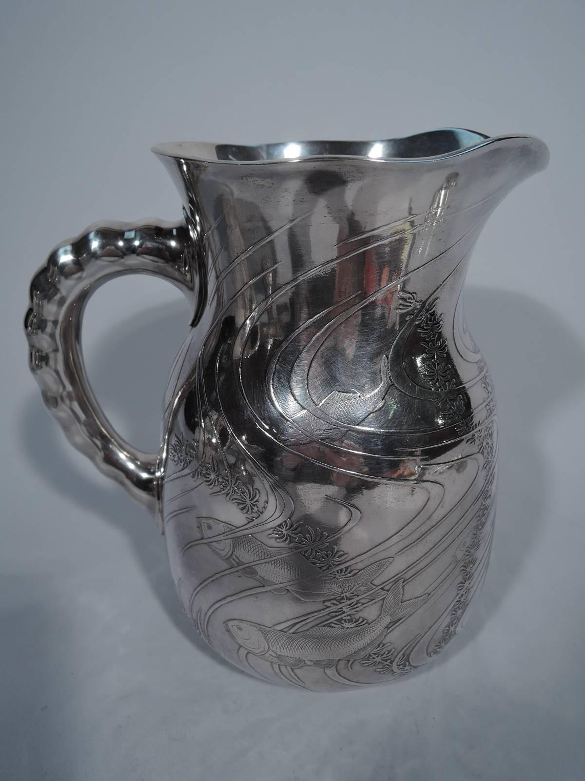 Japonesque sterling silver water pitcher. Made by Dominick & Haff in New York in 1887. Baluster body, undulating rim and C-scroll handle with soft graduated notches. Acid-etched aquatic scene with fish darting among the plants swaying in the
