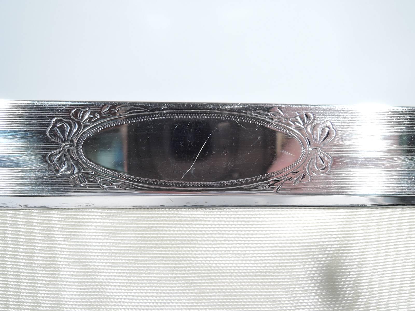 Edwardian sterling silver picture frame. Made by Webster in North Attleboro, Mass., circa 1915. Rectangular window bordered by wraparound lines of varying width. At top beribboned oval (vacant). Nice period look. With glass, silk lining, and velvet