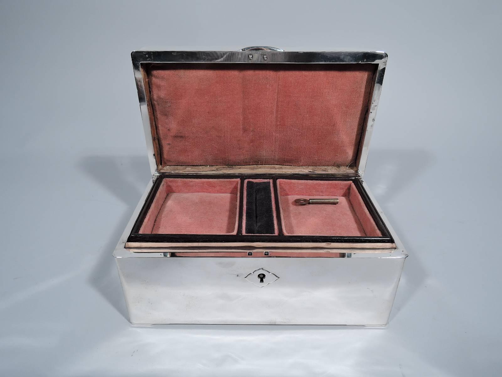 American modern sterling silver jewelry box, circa 1920. Rectangular with straight sides. Cover hinged with curved tab. Keyhole has scrolled lozenge plate. With key. Box and cover interior lined with salmon pink velvet. Detachable stained-wood tray