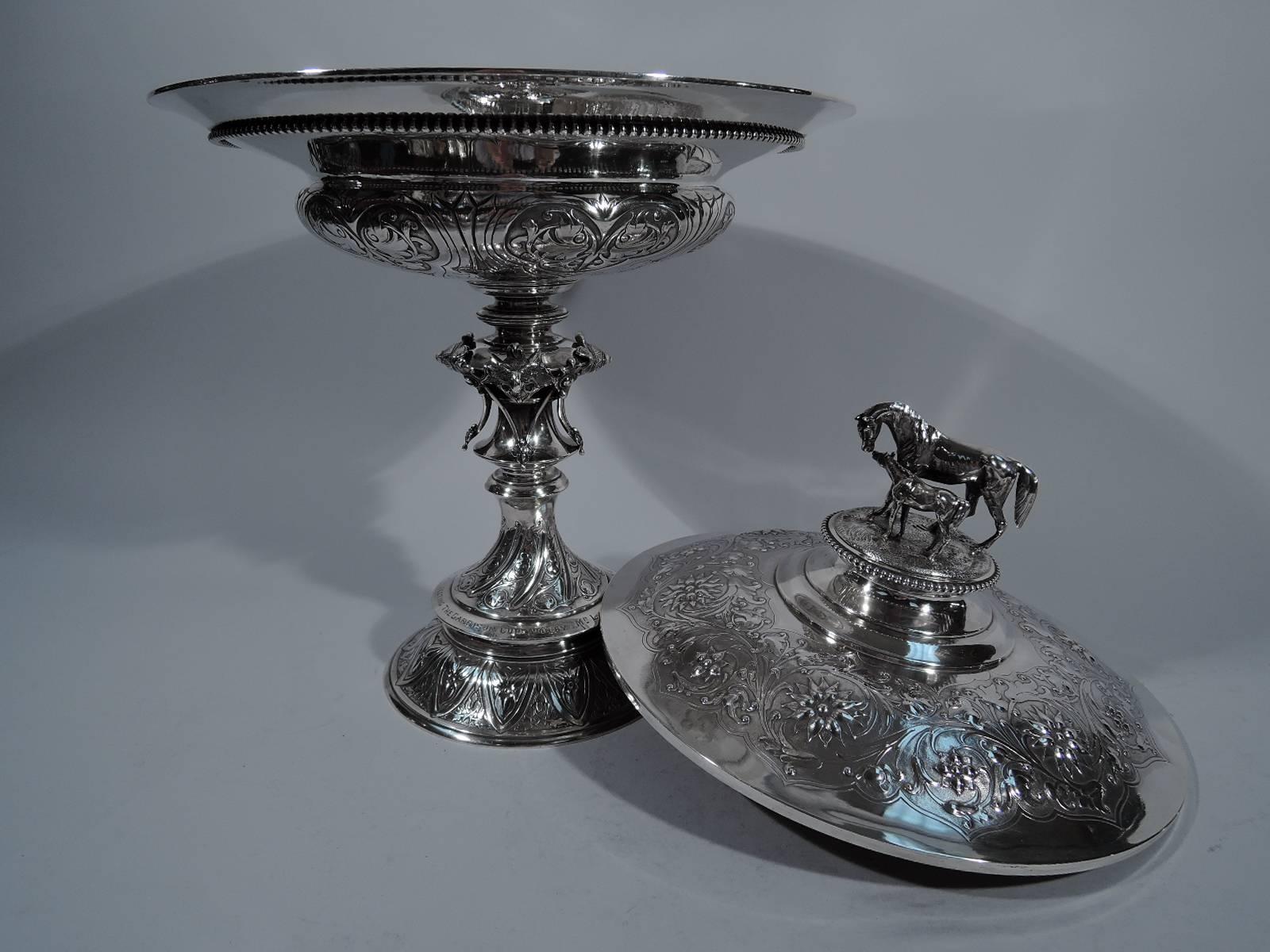 Victorian sterling silver covered trophy cup. Made by Robert Hennell in London in 1853.

Squat and shallow bowl on knopped stem mounted to double-dome foot. Chased and stylized flowers and incised and twisted lines alternating with garlands.