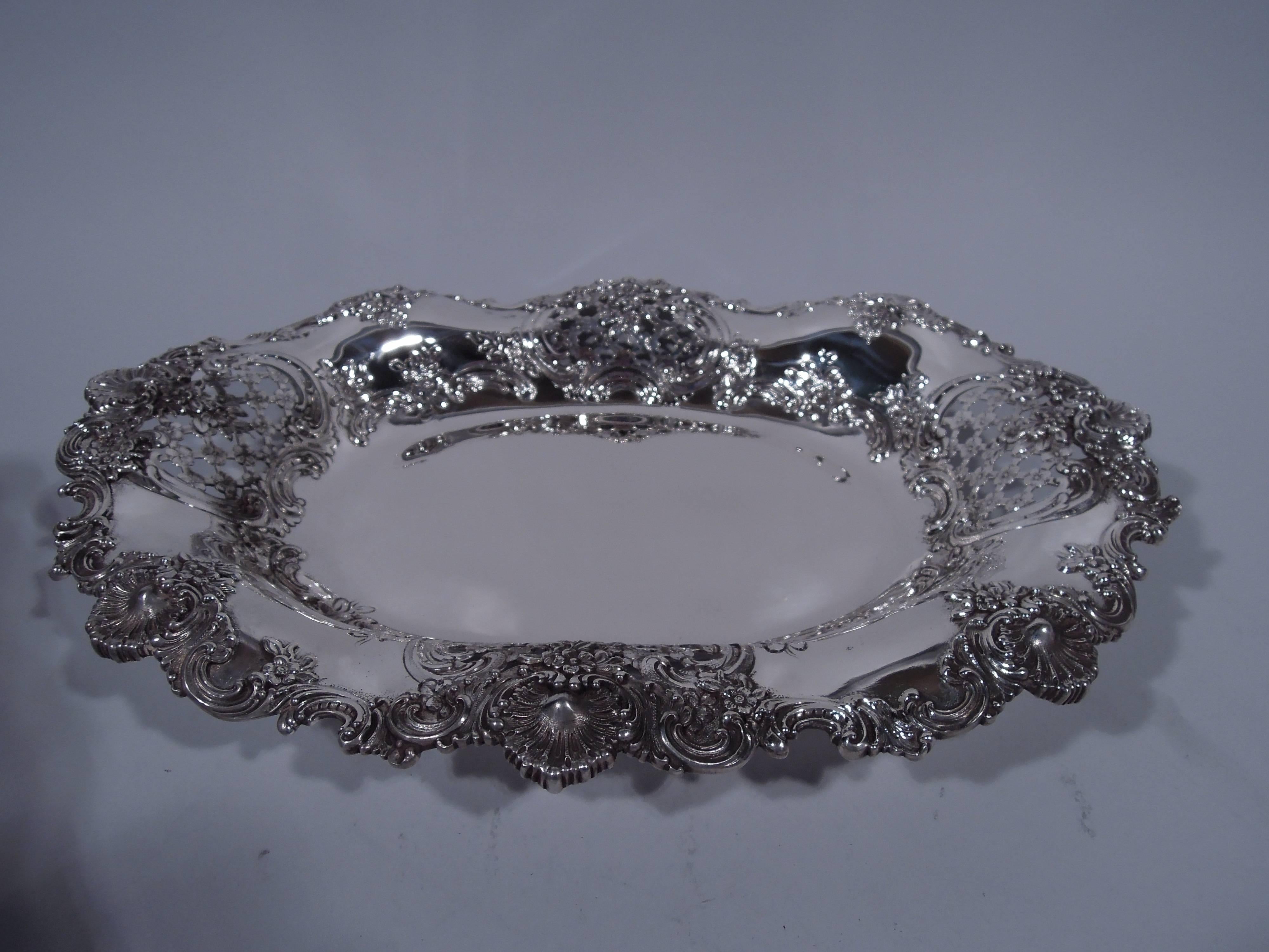 Sterling silver bowl. Made by Tiffany & Co. in New York, circa 1892. Solid oval well and flared wavy rim. Chased flowers and scrolls, and pierced floral lattice. Rim has applied scrolls, flowers, and scallop shells. A great piece of the fancy stuff.