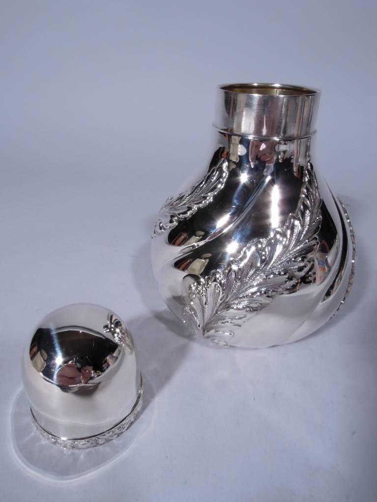 Sterling silver tea caddy. Made by Tiffany & Co in New York. Ovoid with incised and twisted lobes alternating with applied and twisted leaves. Short neck and domed cover with applied repousse band of leaves and flowers. Hallmark includes pattern no.