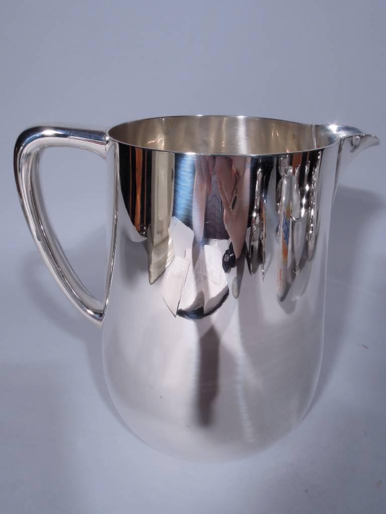 Mid-Century sterling silver water pitcher. Made by Tiffany & Co. in New York. Straight and upward tapering sides, curved bottom, scrolled bracket handle, and small lip spout. Hallmark includes postwar pattern no. 23362 and director’s letter L