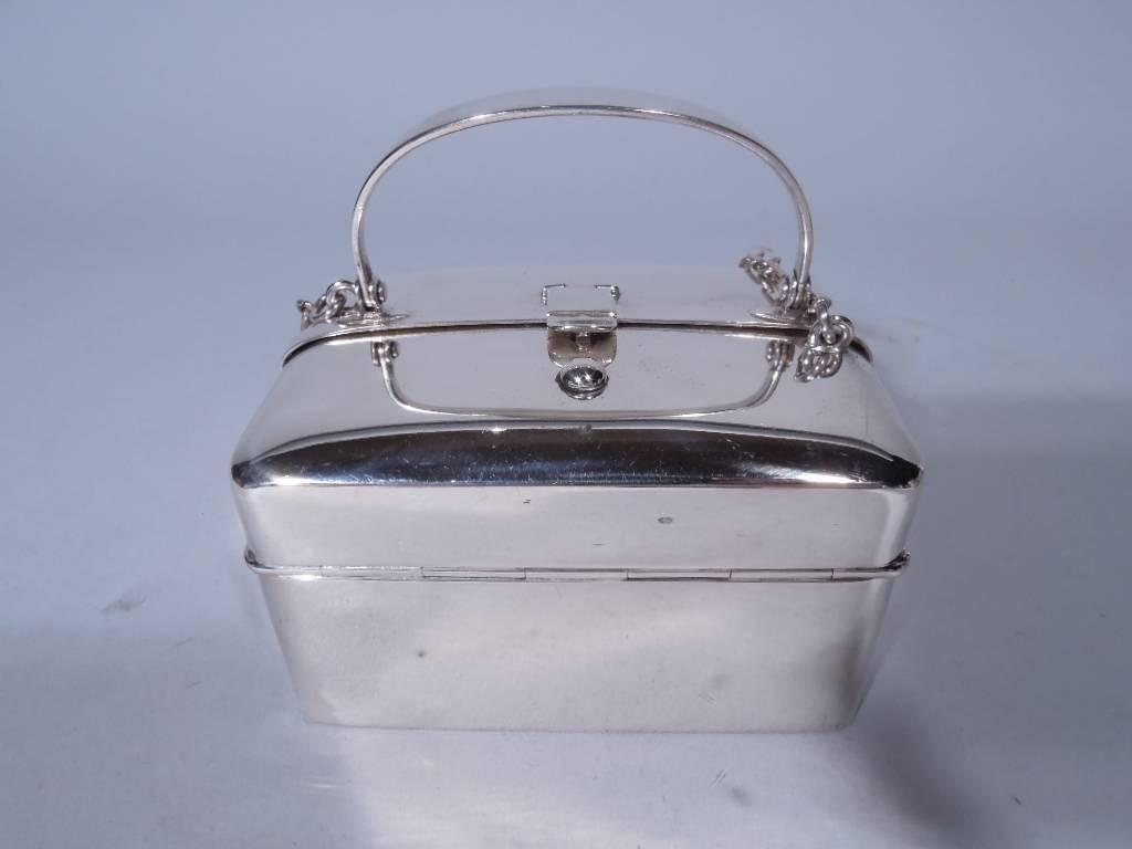 Antique sterling silver “lunchbox” purse. Made by Blackinton in North Attleboro, circa 1920. Rectangular with curved corners. Double hinged cover with hinged hasp, C-scroll swing handle and wrist chain. Interior has three spring coin compartments