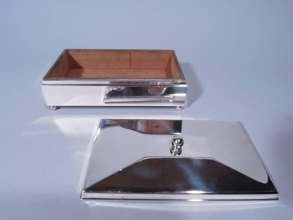 Modern sterling silver box. Made by Manchester in Providence, circa 1925. Rectangular with straight sides and ball corner supports. Cover gently faceted with central ball finial. Box interior cedar lined. Box underside leather lined. Hallmarked.