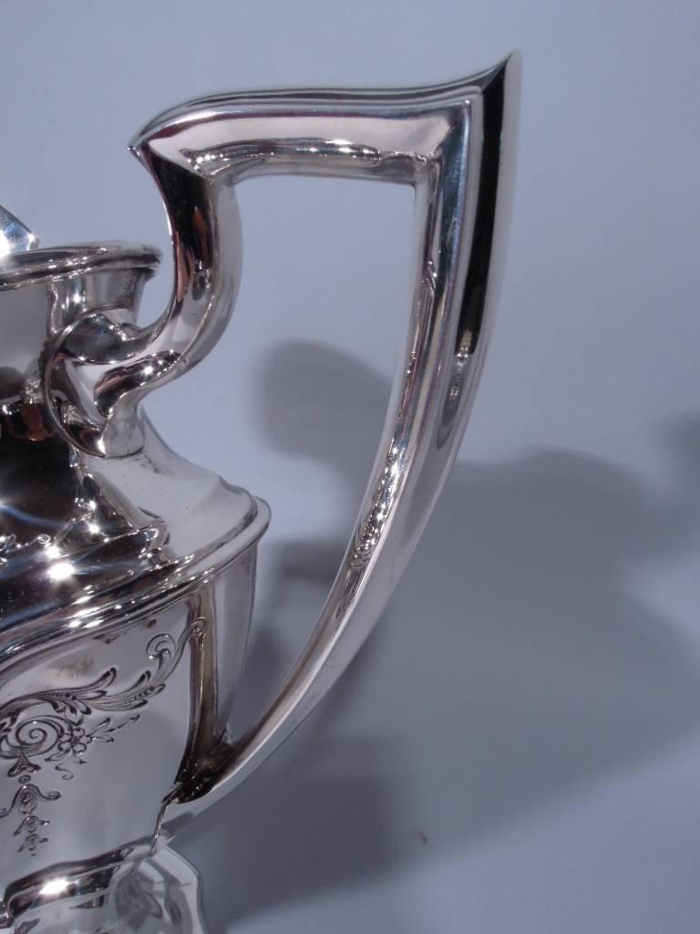 Sterling silver water pitcher in Hepplewhite pattern. Made by Reed & Barton in Taunton, Mass. in 1937. Shaped and tapering body, stepped and shaped foot, helmet mouth and scrolled bracket handle. Engraved foliage and flowers with two oval frames