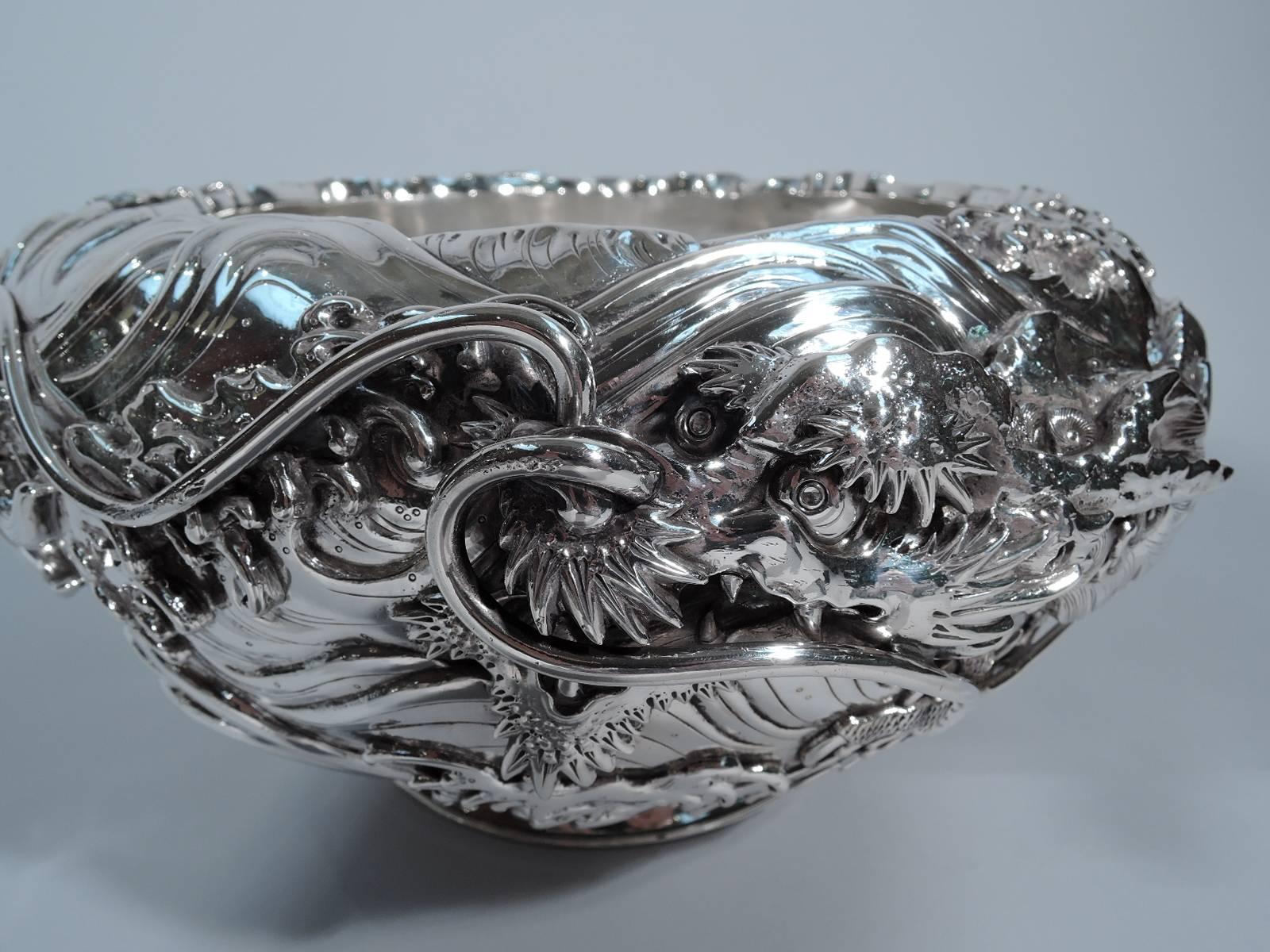 Fantastic Japanese silver bowl with wraparound dragon, circa 1890. Curved sides and collar base. Sculptural relief ornament in form of scaly dragon slithering through wavy water. Details include whiskered snout and swooshing tail fin. Interior