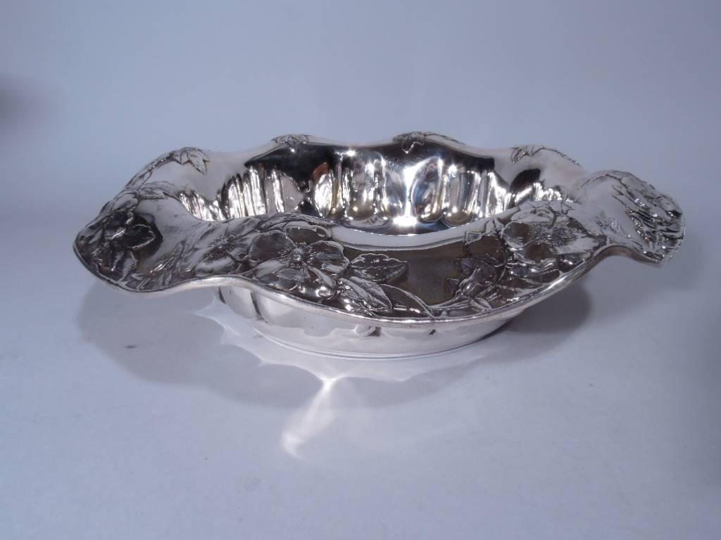 Sterling silver centerpiece bowl. Made by Tiffany & Co. in New York, circa 1910. Straight sides with two thumbprint lobes alternating with solid space. Wavy turned-down petal rim with applied flowers. Hallmark includes pattern no. 16346A and