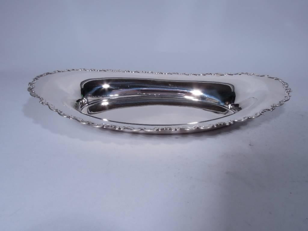 Sterling silver bread tray. Made by Whiting in Providence, circa 1920. Oval well and asymmetrical rim with applied C- and S-scrolls. Hallmark includes no. 3357. Very good condition.

Dimensions: H 2 1/8 x W 14 x D 7 5/8 in. Weight: 15.5 troy