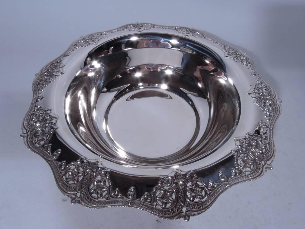 Edwardian sterling silver bowl. Made by Tiffany & Co. in New York, ca. 1910. Round and plain well with scrolled rim. Rim ornament includes flowers set in pierced roundels, applied leaves, as well as scrolled and interlaced bands inset with stylized