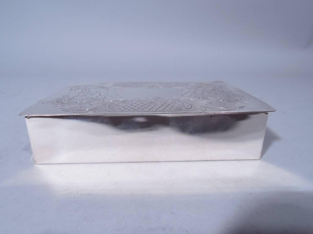 American sterling silver box, circa 1915. Rectangular with straight sides. Cover hinged, flat and overhanging. On cover is vacant center surrounded by engraved flowers, foliage and diaper pattern. Hallmarked “Sterling Hand Made 225/3”. Weight: 5.8
