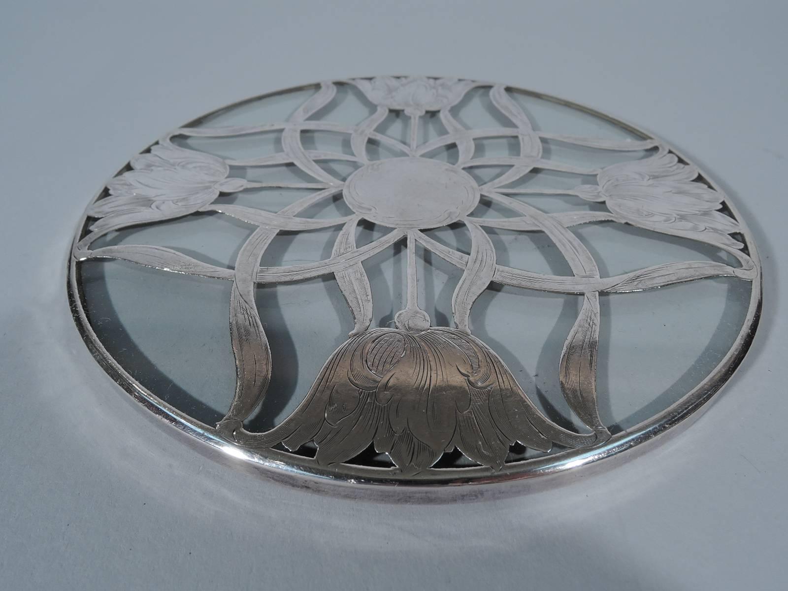Art Nouveau clear glass trivet with floral silver overlay. Open blooms brush against the rim and the stems and leaves intertwine to form a central star with solid center (vacant). Faint hallmark. Very good condition and patina.

Dimensions: H 1/4
