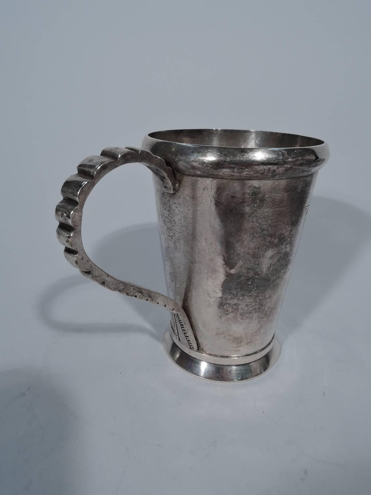 South American 900 silver mug. Handmade. Tapering sides and skirted foot. Interesting scroll handle has graduated notching and V-form terminal. Engraved flower and scrolled band (vacant). Hallmarked on handle “PE 900.” Nice finish.

Dimensions: H
