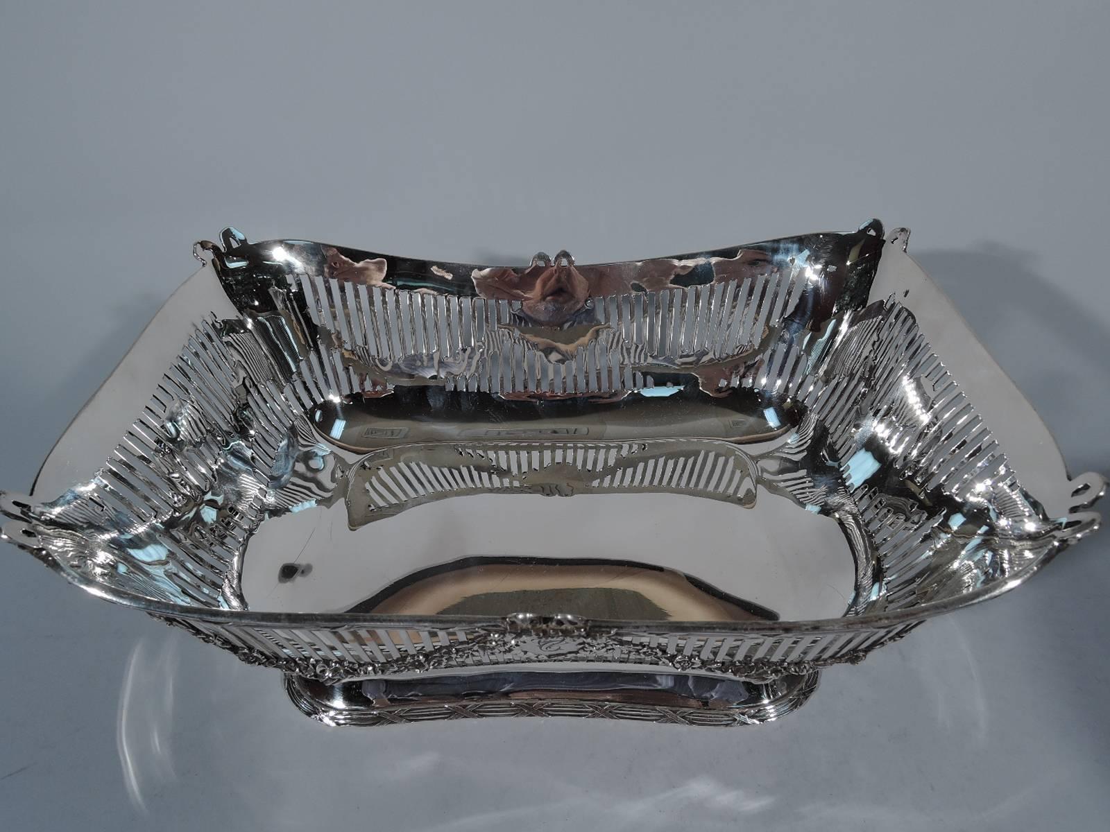 Edwardian neoclassical sterling silver bread basket. Made by Graff, Washbourne & Dunn in New York, circa 1910, for JE Caldwell in Philadelphia. Rectilinear with rounded corners and asymmetrical rim. Sides have linear piercing with applied garlands