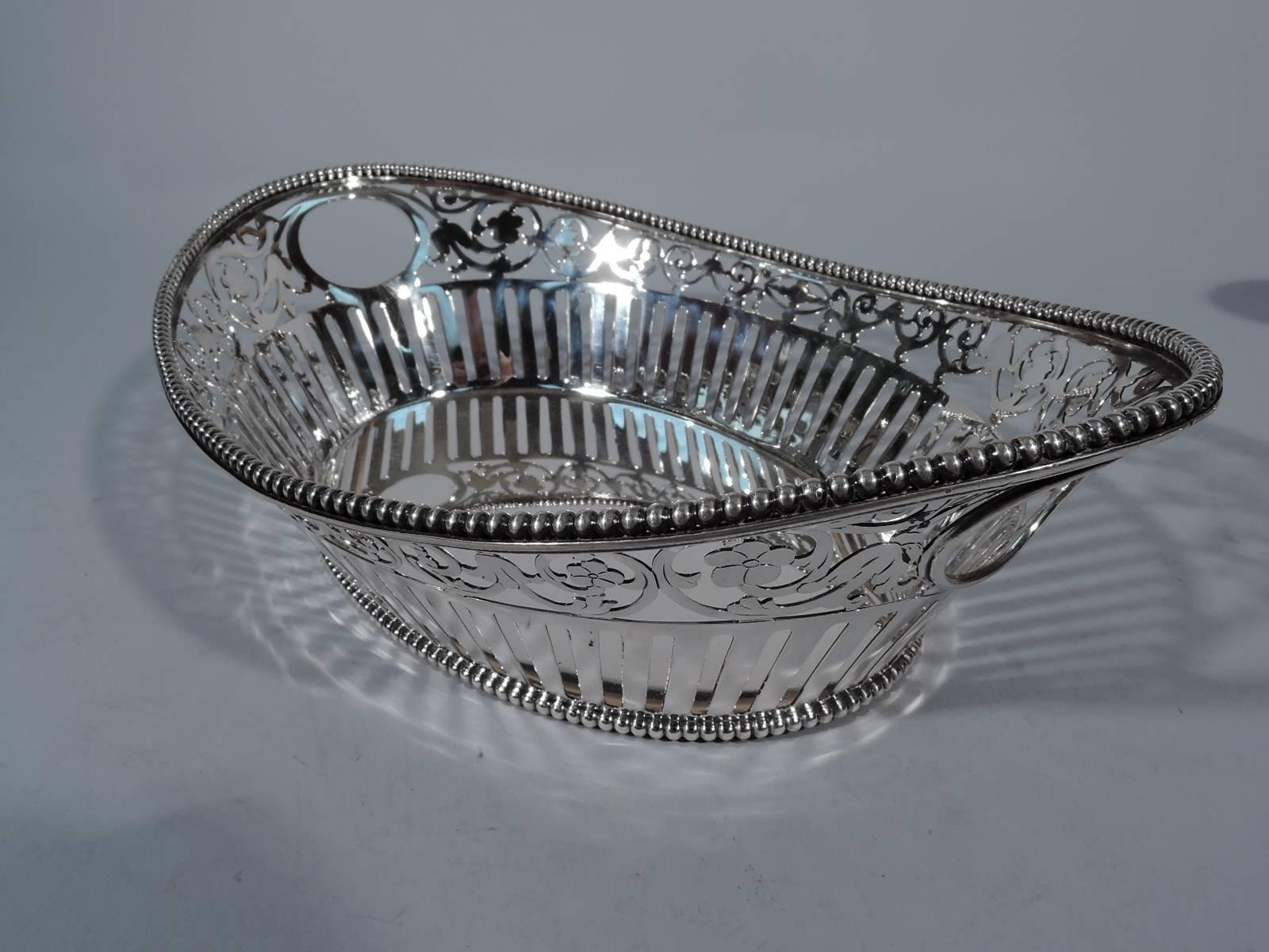 Sterling silver bread basket. Made by Howard & Co. in New York in 1889. Solid oval well with tapering sides and asymmetrical rim. Sides pierced with linear, floral, and rinceaux ornament. Oval cut-out end handles. Rim and base beaded. Elegant and
