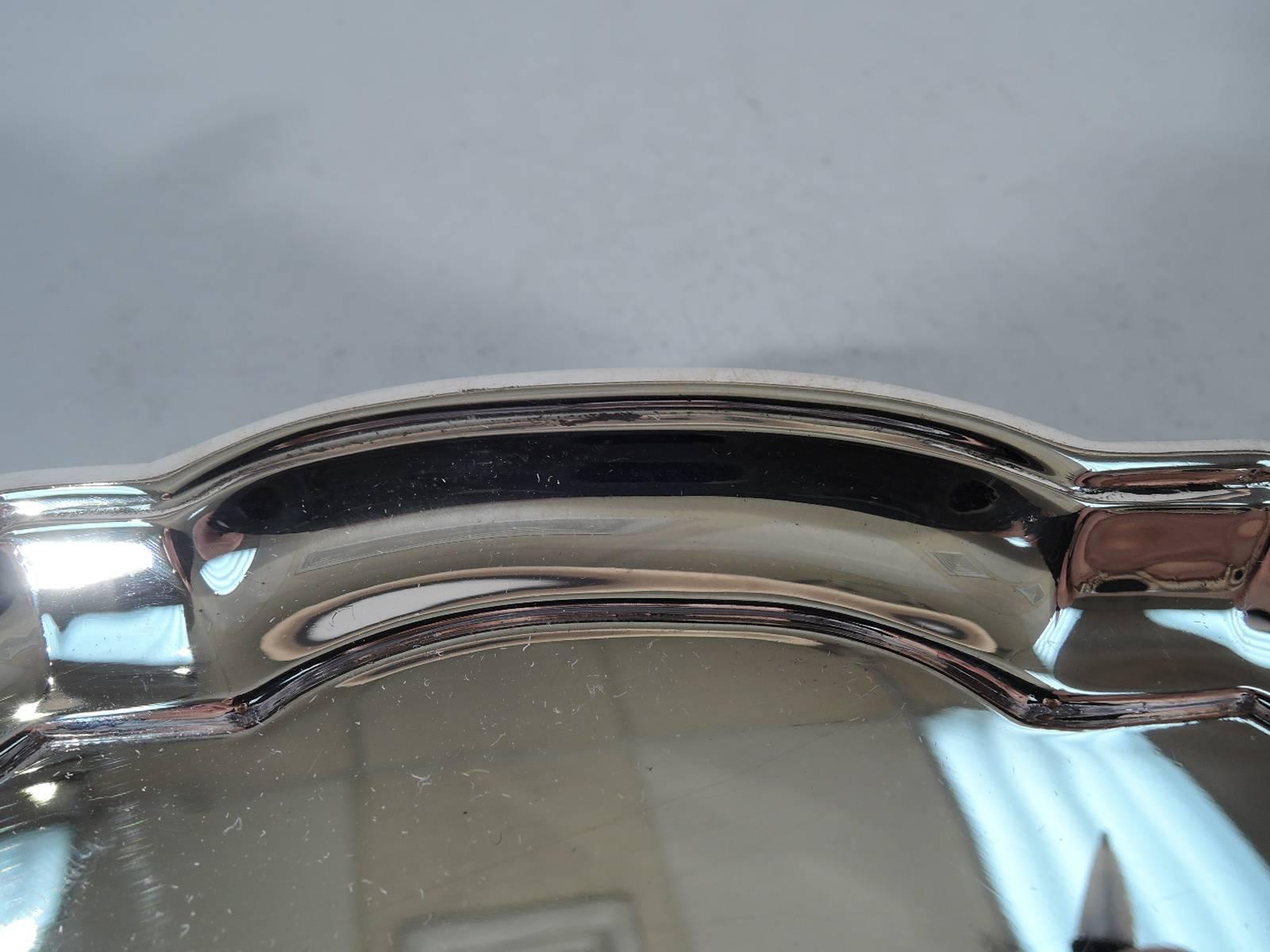 Georgian style sterling silver salver. Made by Tiffany & Co. in New York. Circular with molded curvilinear rim. Rests on four capped volute scrolls. Hallmark includes pattern no. 21745 (first produced in 1931) and director’s letter M (1947-56). Very