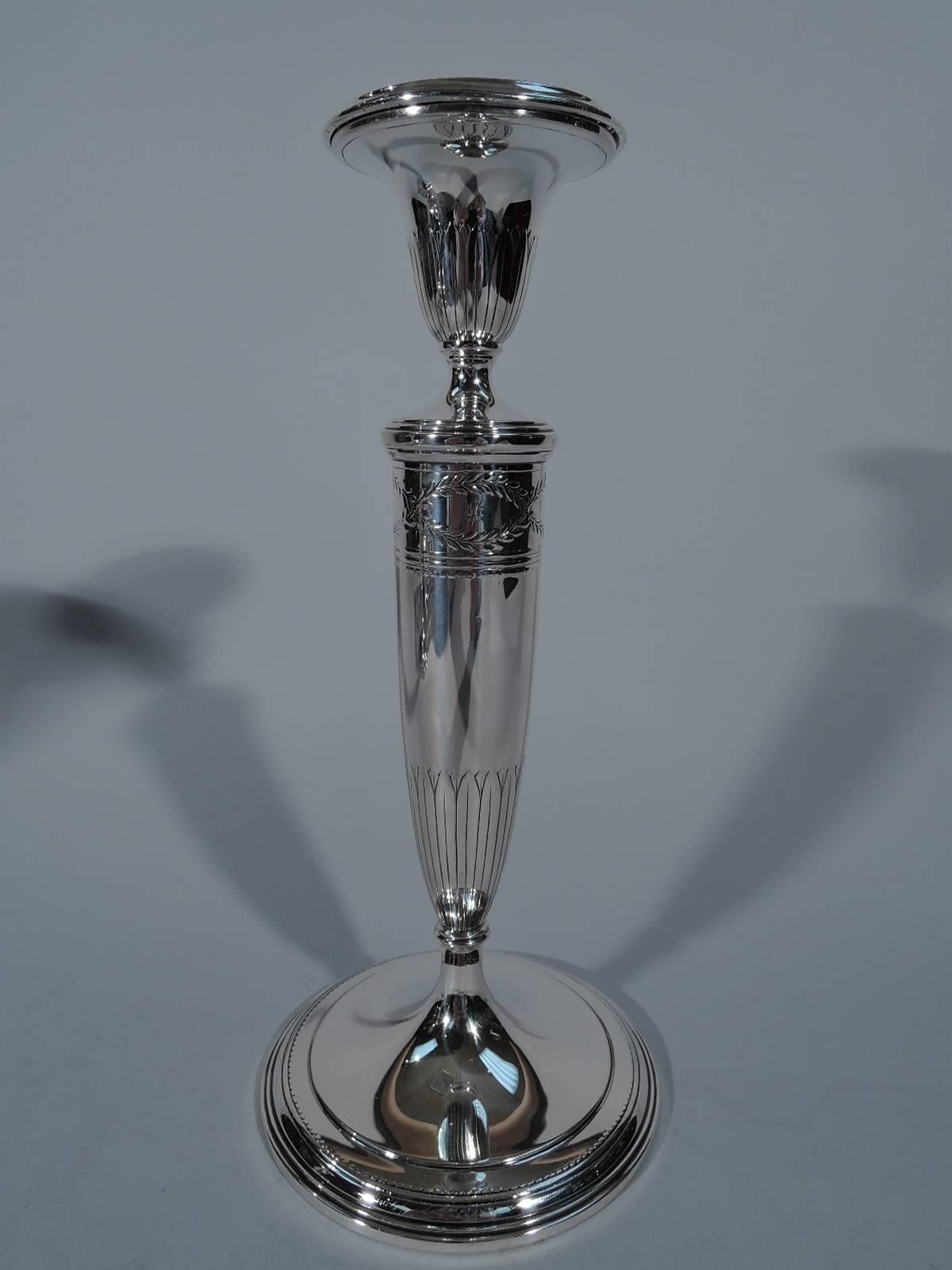 Pair of sterling silver candlesticks in Winthrop pattern. Made by Tiffany & Co. in New York, circa 1922. Each: Tapering shaft on stepped foot. Conical socket with detachable bobeche. Chased and stylized foliage on shaft and socket bases. Traditional