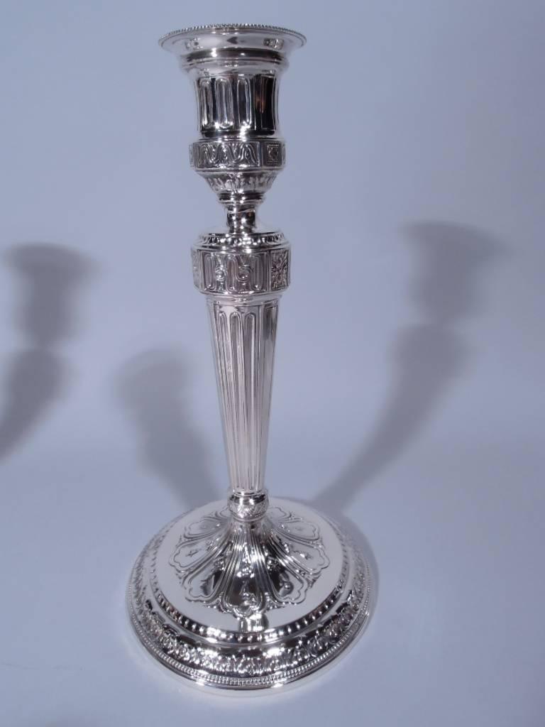 Pair of neoclassical sterling silver candlesticks. Made by Tiffany & Co. in New York, circa 1914. Each: tapering columnar shaft on raised and stepped foot. Urn socket and detachable bobeche. Traditional ornament, including dentil, beading, leaves,