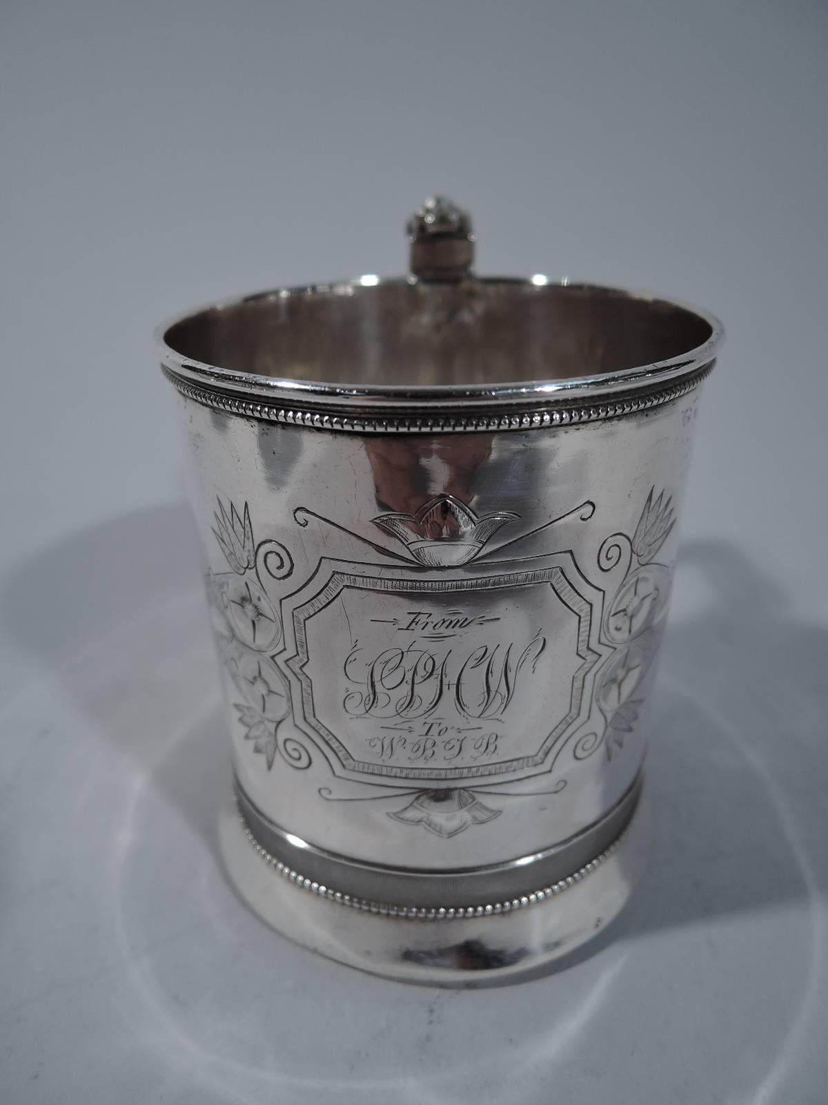 Coin silver christening mug. Made by Gorham in Providence, circa 1865. Straight sides, spread base, and scroll bracket handle with bug cap. Curvilinear frame surrounded by advanced stylized ornament. Script presentation engraved in frame. Beading