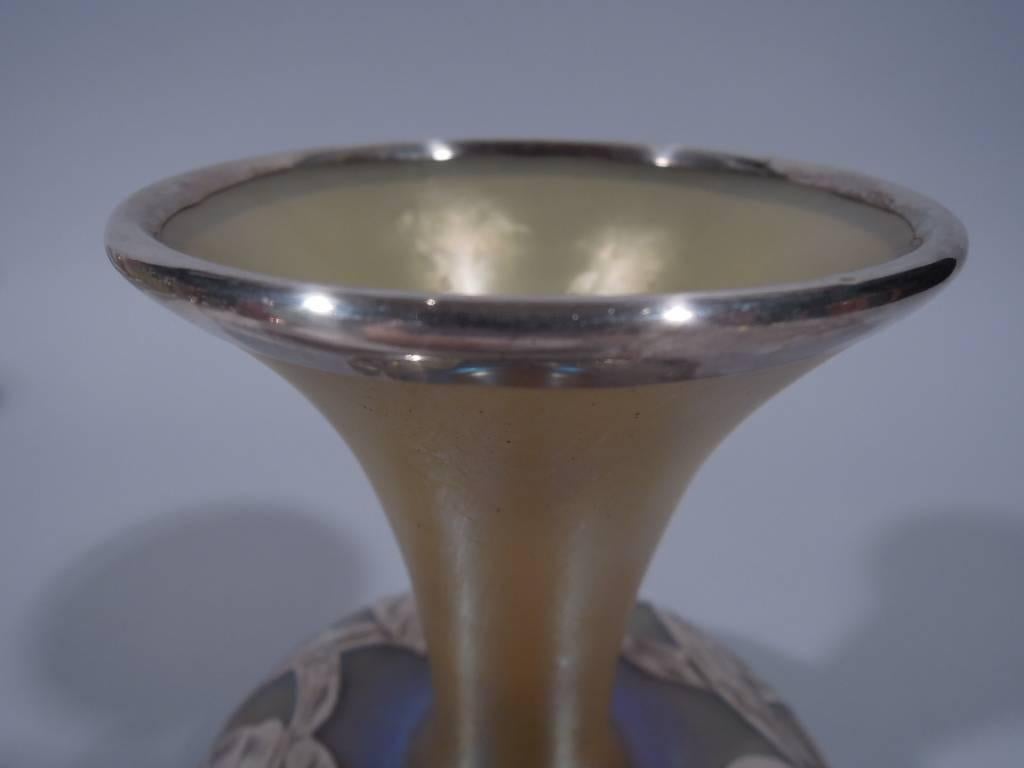 Art Nouveau iridescent glass vase with silver overlay. Made by Alvin in Providence, circa 1900. Bellied bowl with conical neck and wide mouth. Glass is gold. Floral silver overlay a ring of big blooms joined by crisscrossing leaves. Hallmark