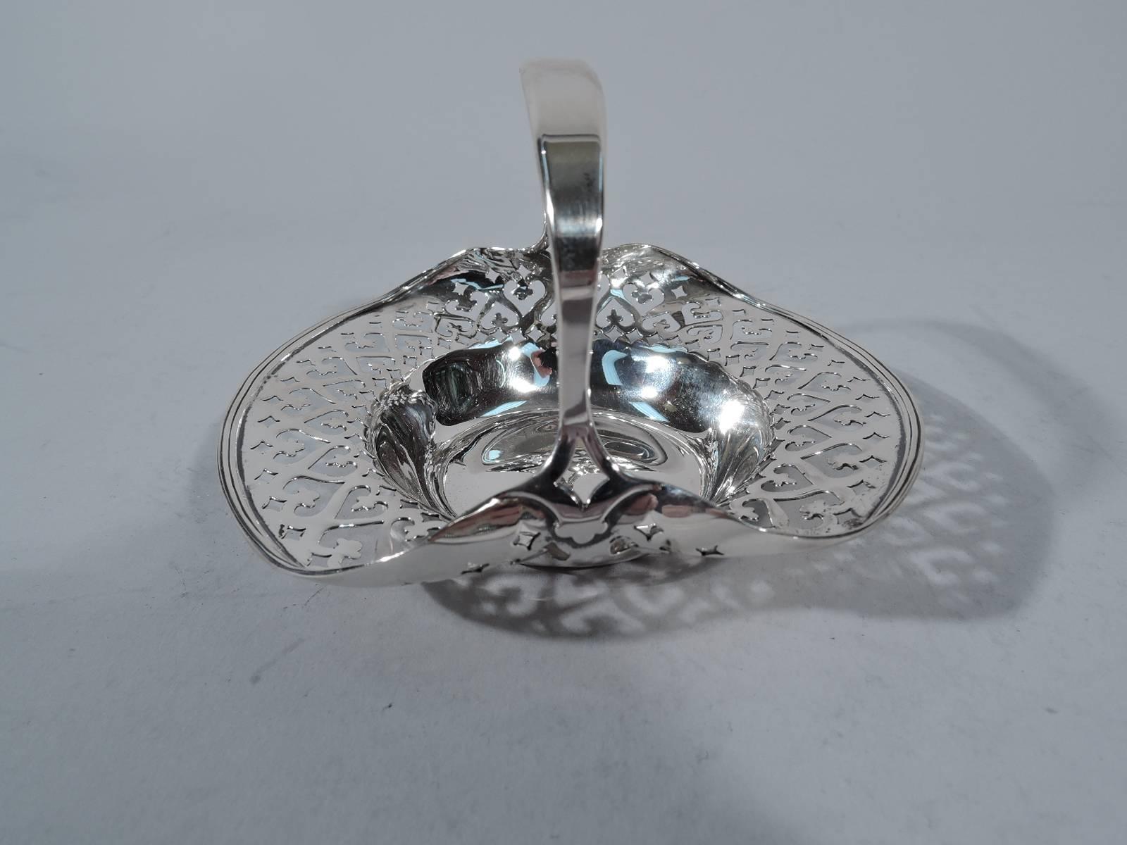 Sweet and old fashioned sterling silver basket. Made by Tiffany & Co. in New York, circa 1910. Circular well and pierced and molded rim. Sides “tugged” upwards by stationary bracket handle. Hallmark includes pattern no. 16665 and director’s letter m