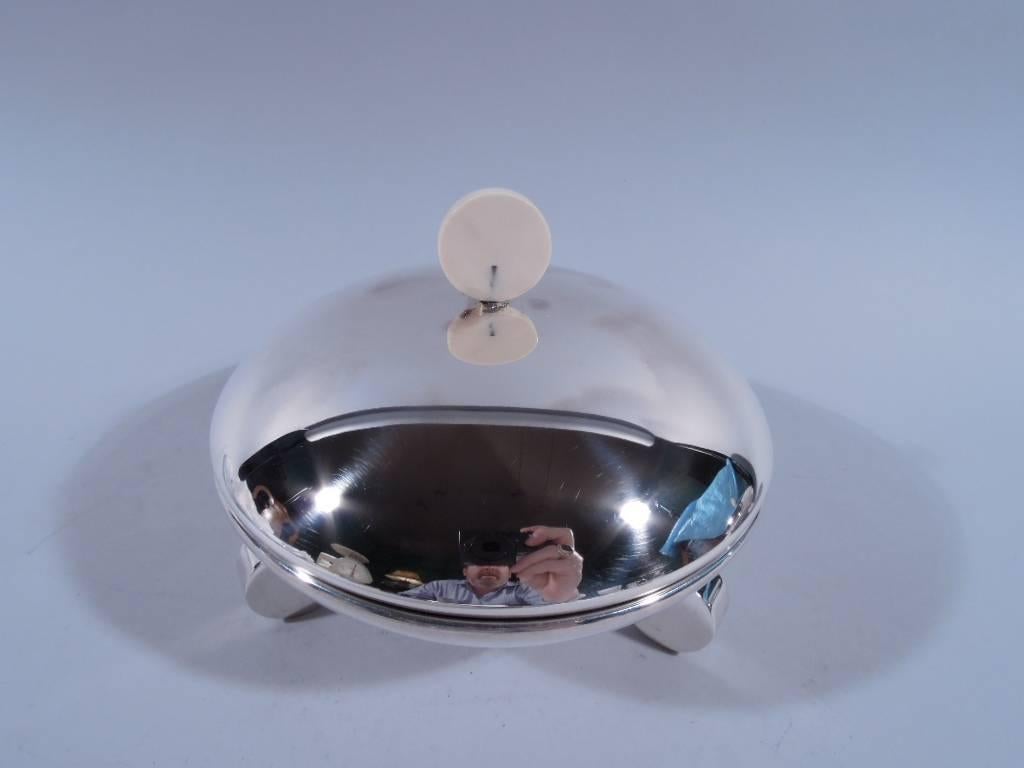 Modern sterling silver covered serving dish. Shallow and curved bowl and cover. Cover has disc finial. Rests on three disc supports. Hallmarked. Fine condition.

Dimensions: H 5 x D 5 7/8 in. Weight: 16 troy ounces. BP130.