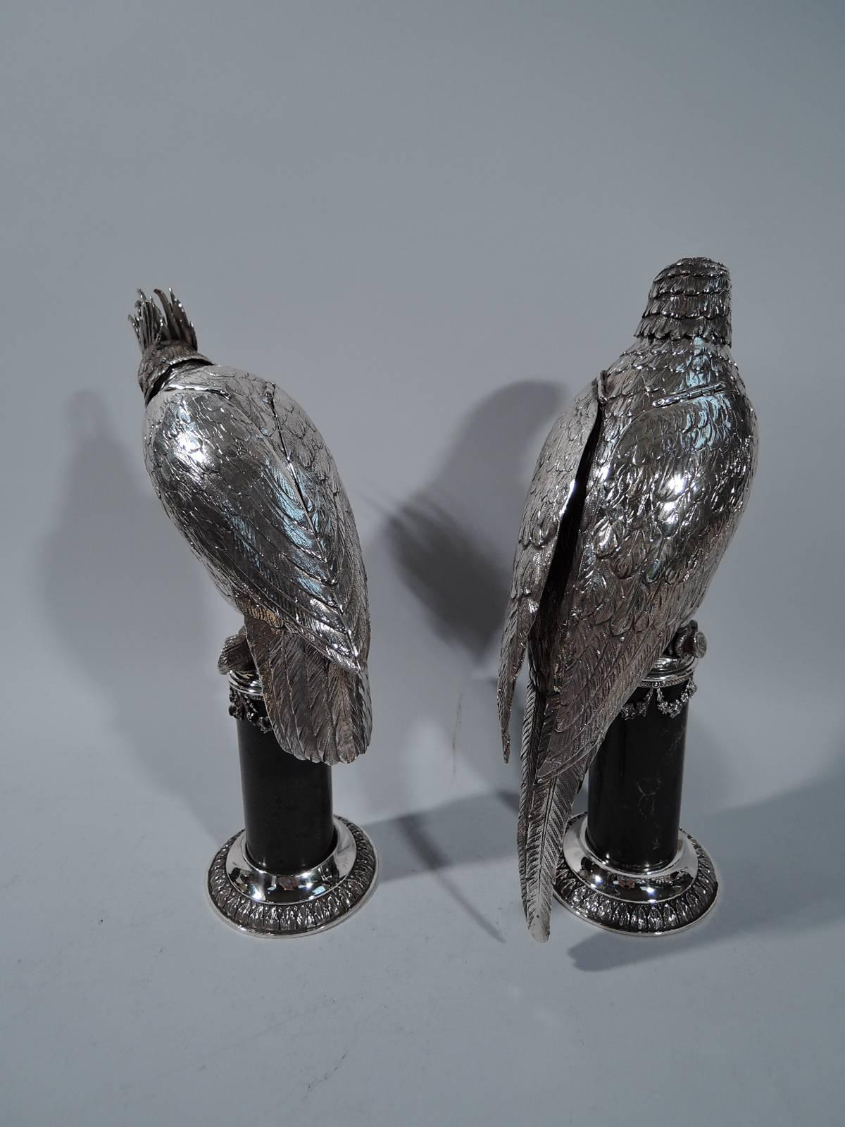 Pair of German silver parrot spice boxes, circa 1890. Each: Full downy body with hinged wings and scaly talons gripping a wood perch. Head detachable. A male and female couple. The male has a fancy crown and looks down. The female is on alert with