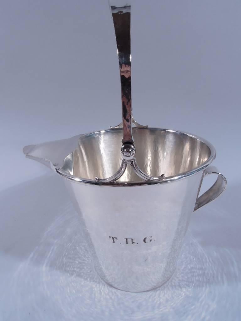Craftsman sterling silver ice bucket. Made by Frank M. Whiting in North Attleboro, circa 1910. Straight and tapering sides, small scroll handle, covered spout, and tapering c-scroll swing handle on split mounts. Visible hand hammering. Shaded block