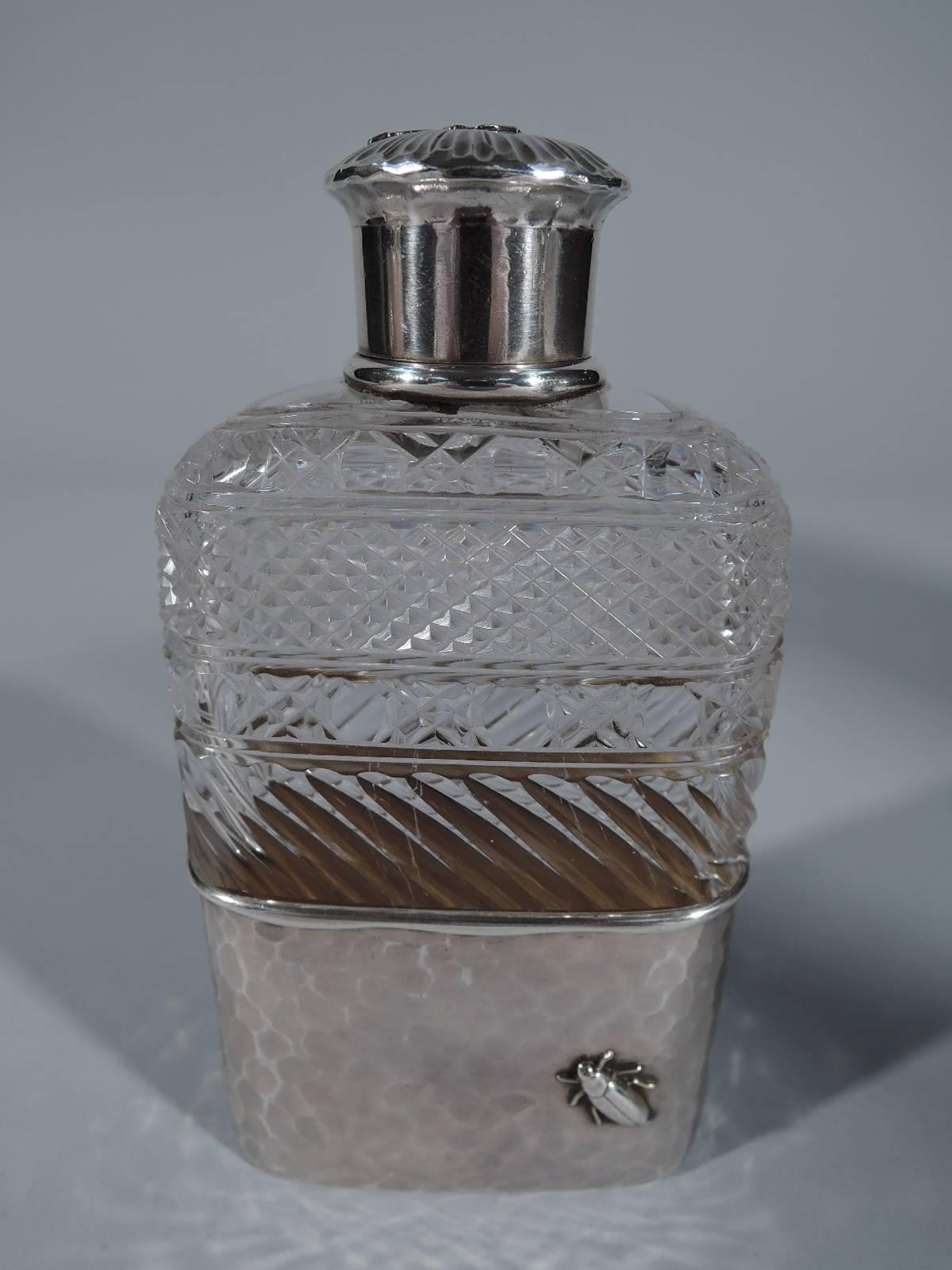 Brilliant-cut-glass and sterling silver flask. Made by Tiffany & Co. in New York, circa 1879. Clear glass with brilliant-cut ornament on top half. Bottom has detachable cup in hand-hammered sterling silver with applied bug and leaves. Short neck