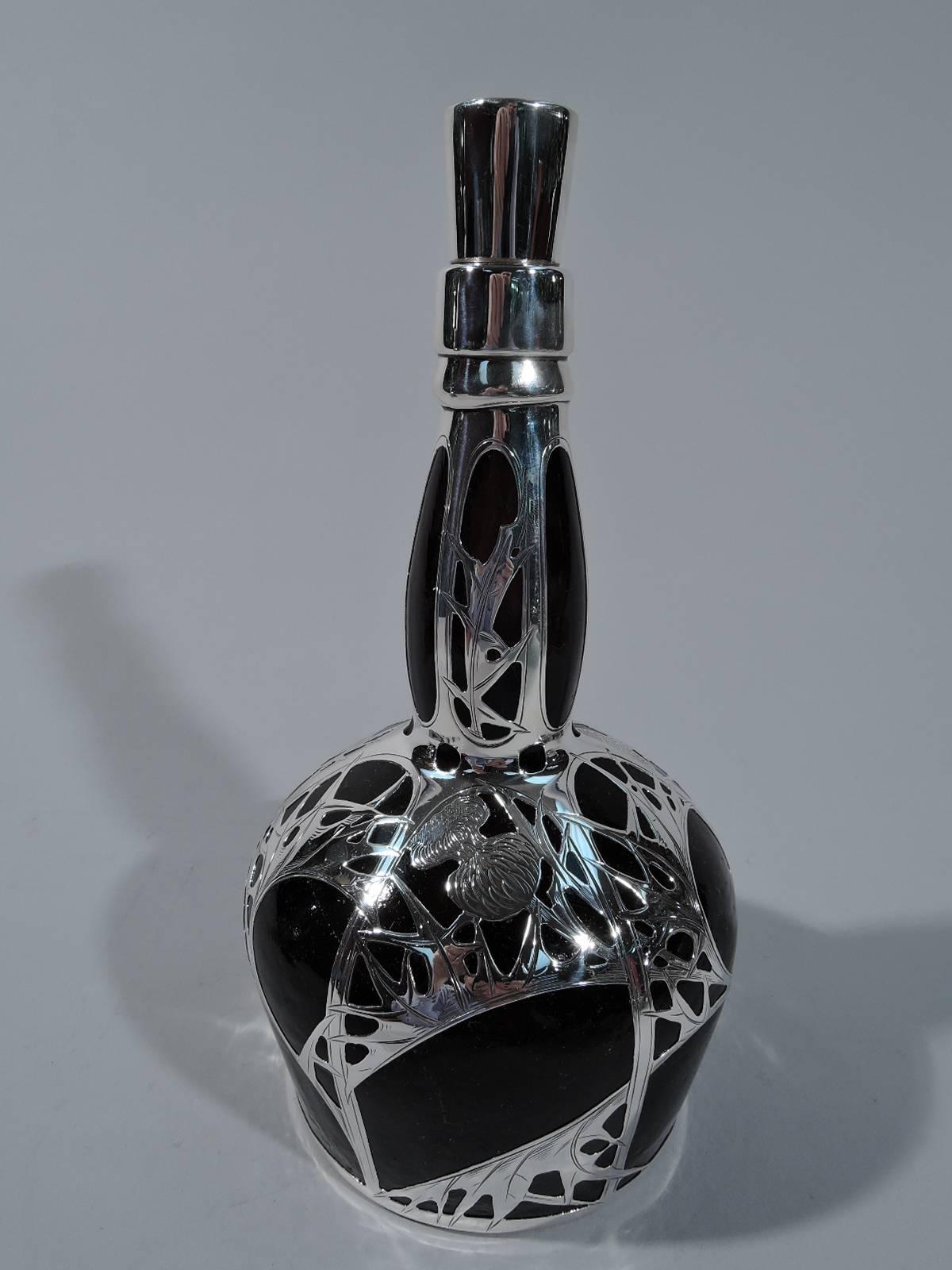 Glass scotch whisky decanter with silver overlay. Made by Gorham in Providence, circa 1900. Bell-form bowl with baluster neck. Glass is thick and rusticated, and dark olive green to brown. Silver overlay in form of prickly, blossoming thistle. Plain