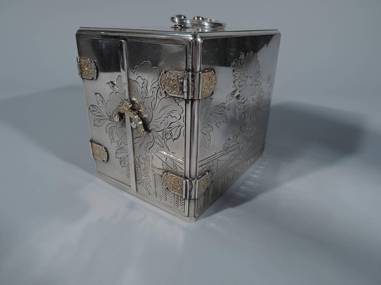 Japanese silver jewelry box, circa 1910. Straight sides with loose-mounted trefoil handle. Sides and top have engraved chrysanthemums, birds, and blossoming prunus branches. Front has two hinged doors with ornamental hinge plates and scrolled hasp.
