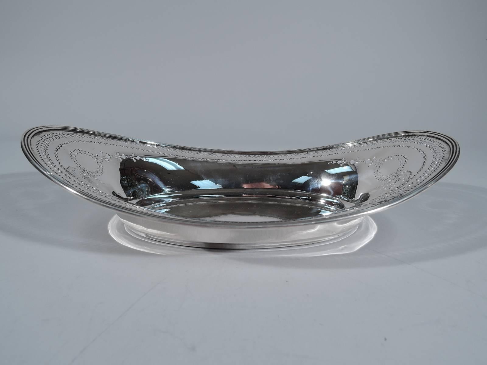 Edwardian sterling silver bread tray. Made by Tiffany & Co. in New York, circa 1912. Oval well and reeded asymmetrical rim. Pierced geometric border and at ends stylized wreath and garland. Hallmark includes pattern no. 18198B (first produced in