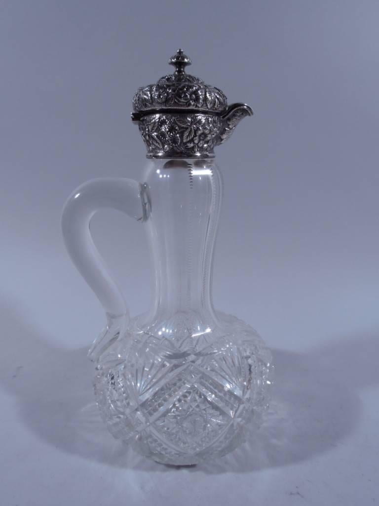 Clear cut-glass and sterling silver decanter. Made by Jacobi & Jenkins in Baltimore, circa 1900. Baluster neck, globular body and S-scroll handle. Cut ornament. Sterling silver mount and hinged cover have dense floral repousse on stippled ground.